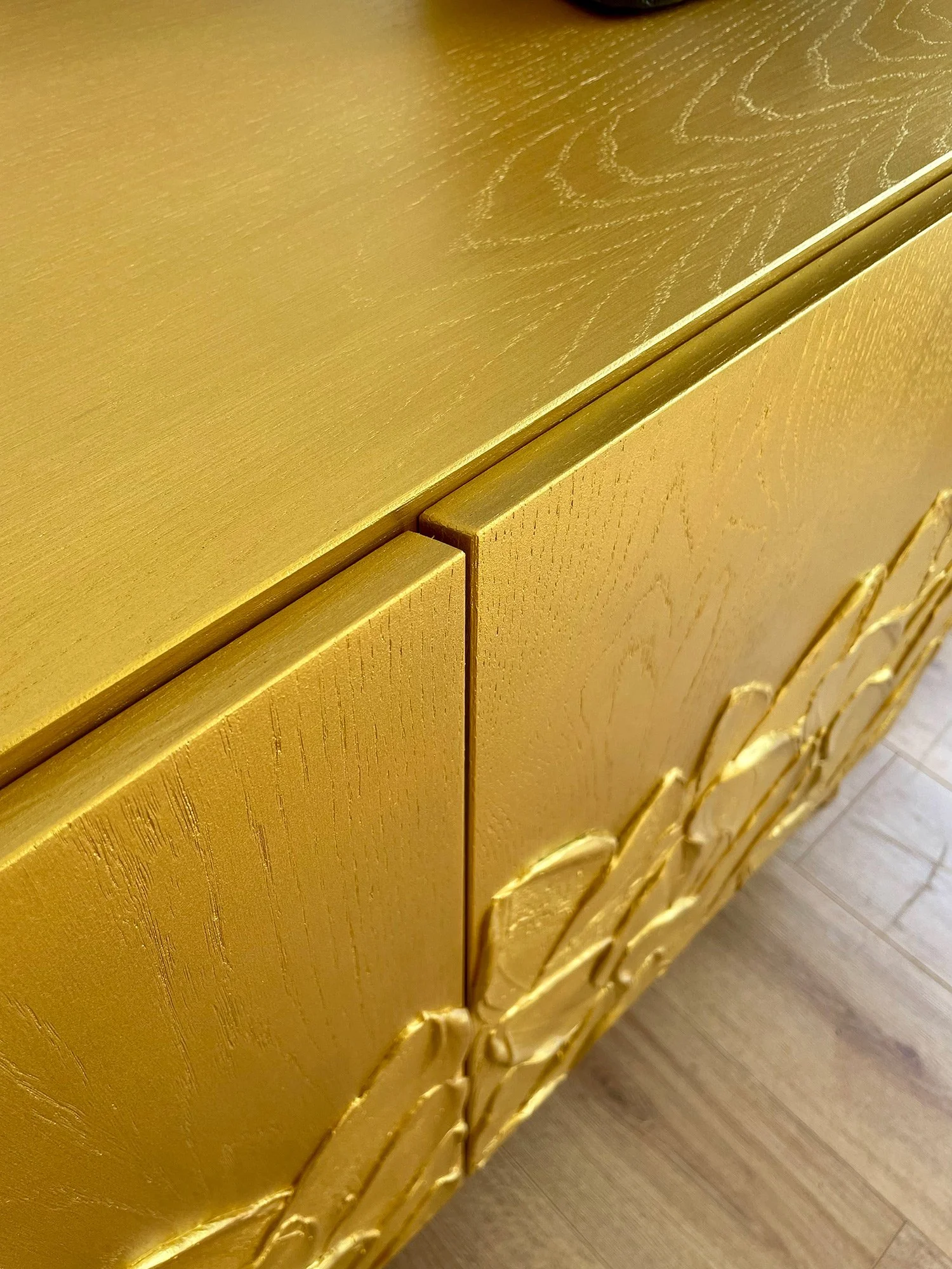 Detail shot of the top edge showing the expert mitred door handles and smooth gold finish.