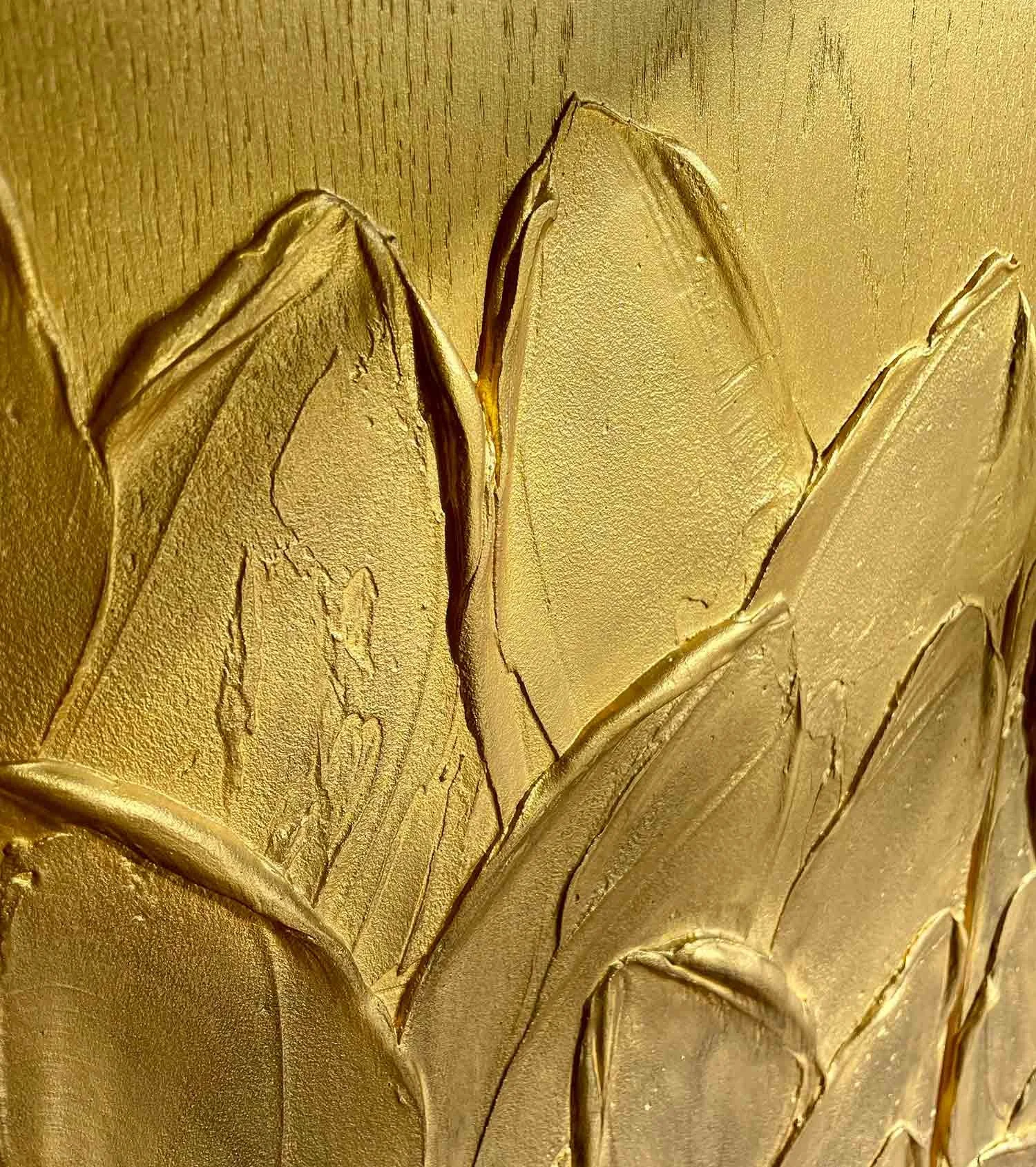 Close-up detail of the hand-sculpted leaf pattern with dark shadowing on a metallic gold background.
