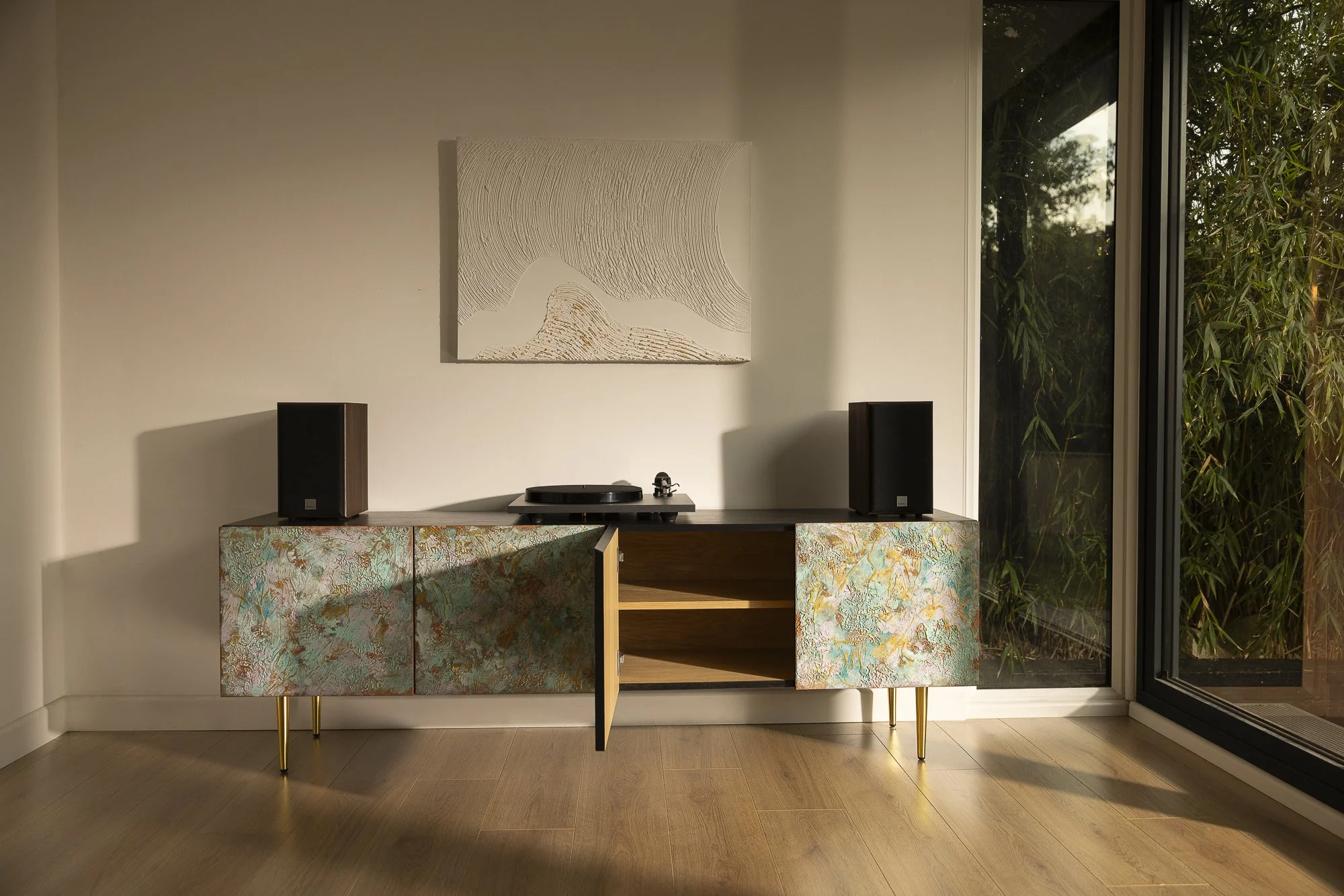Large textured sideboard with 4 colourful doors and gold straight cone feet. One door is open, revealing an Oak interior with a shelf.