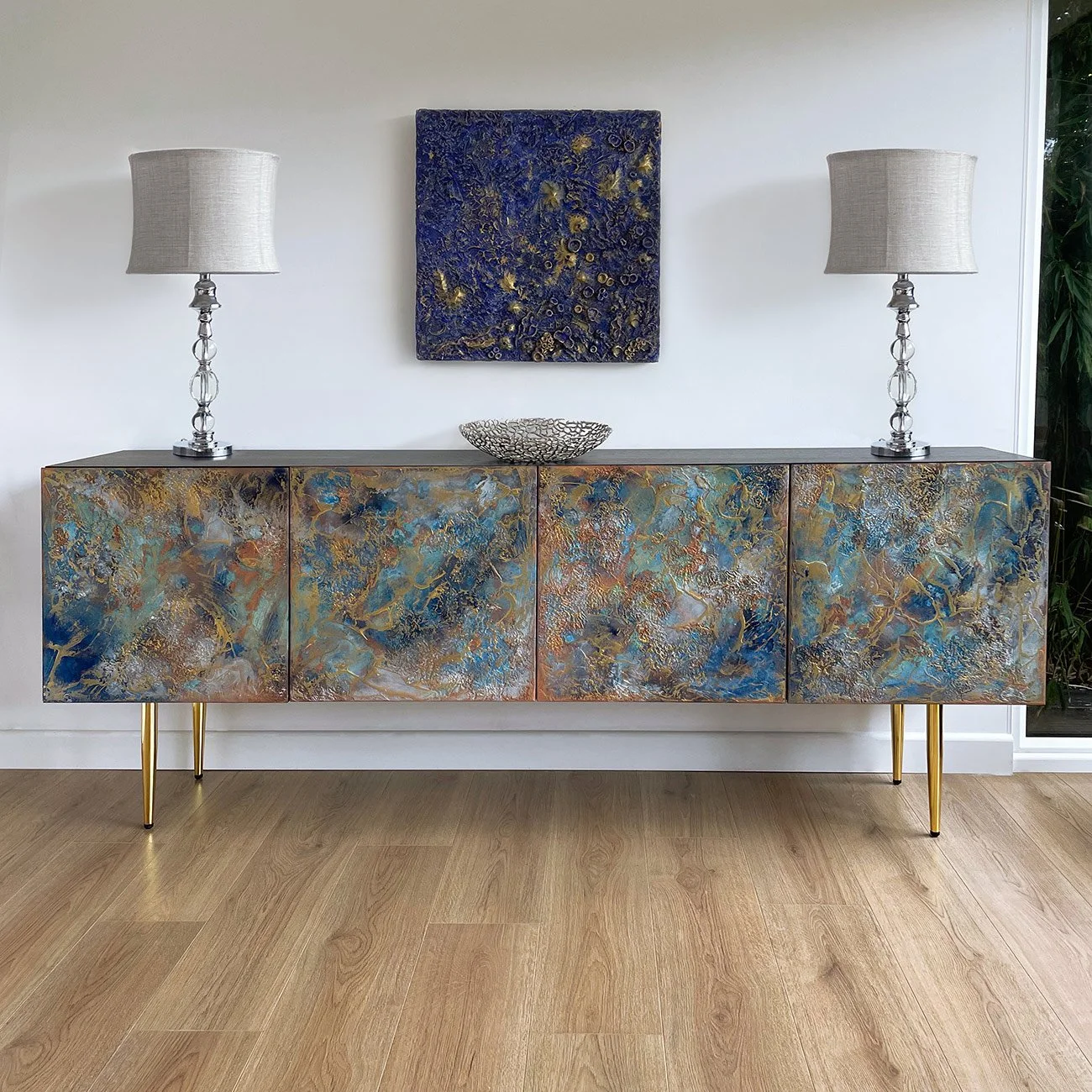 Perspective view of the Midnight Galaxy textured credenza, showing the continuous flow of hand-painted blue and metallic gold abstract patterns across the side and front panels.