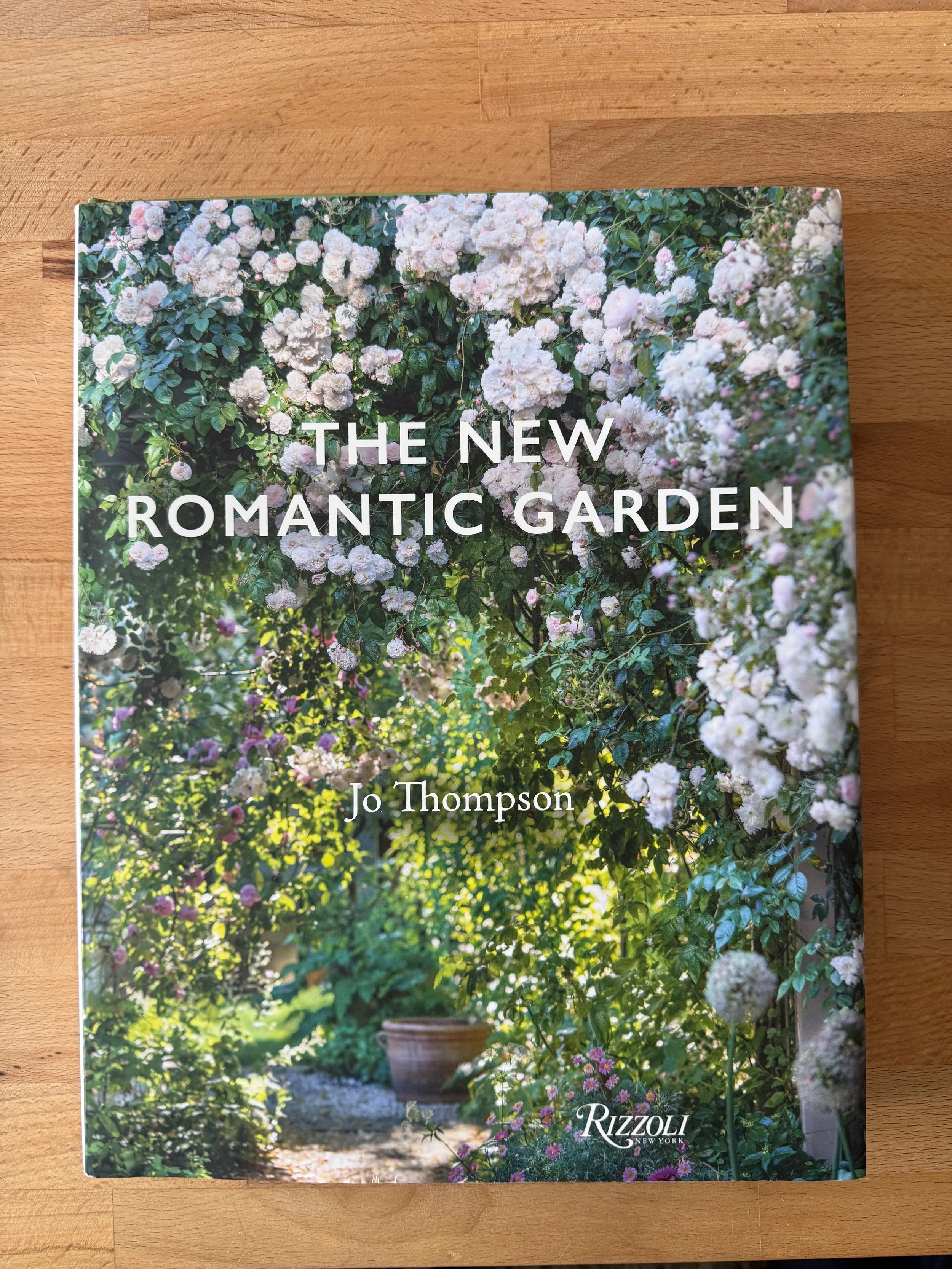 the new romantic garden book by jo thompson on a wood coffeetable