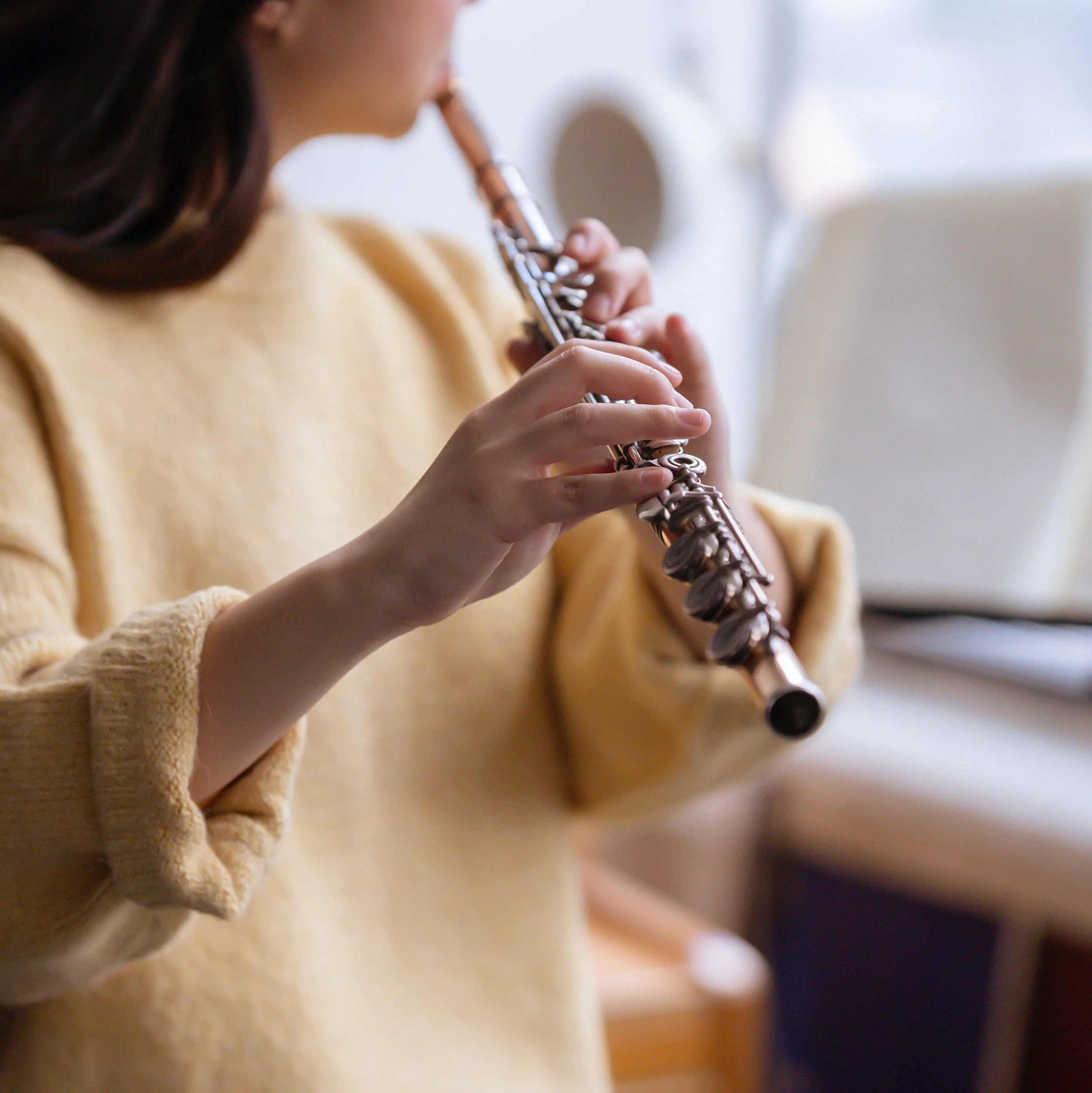 Woman in yellow sweater practicing the flute