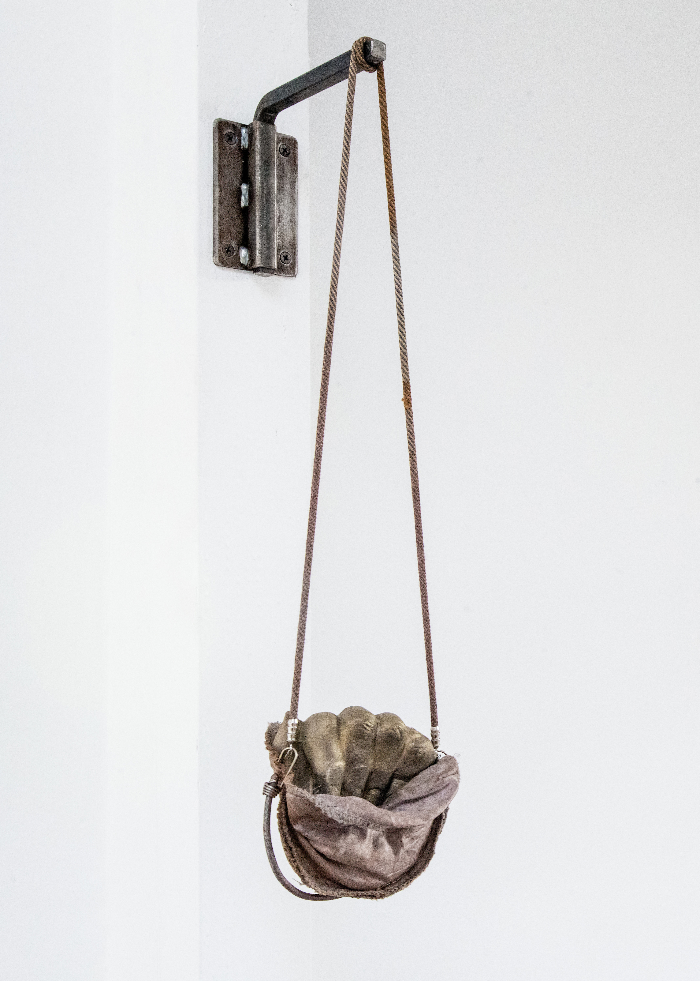  Jenine Marsh,  fist in pocket , 2018. Rust-stained shoulder-pads, necklace cord, bungee cord, staples, wire, powdered pigment, gypsum cement, steel hardware     