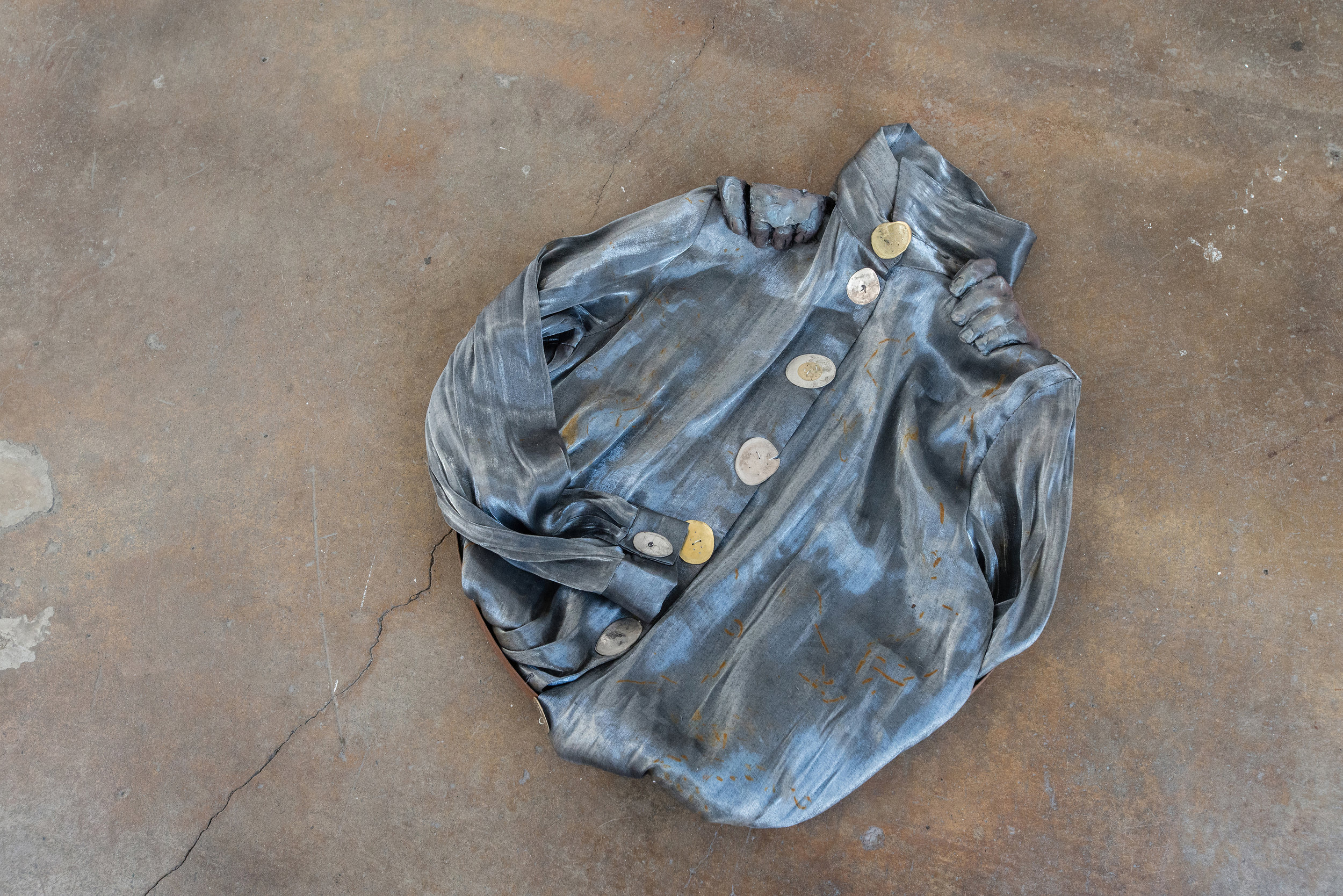  Jenine Marsh,  contortion (steel) , 2018. Found metal ring, rust-stained blouse, train-flattened and drilled coins of mixed currencies, wire, gypsum cement, powdered pigment     