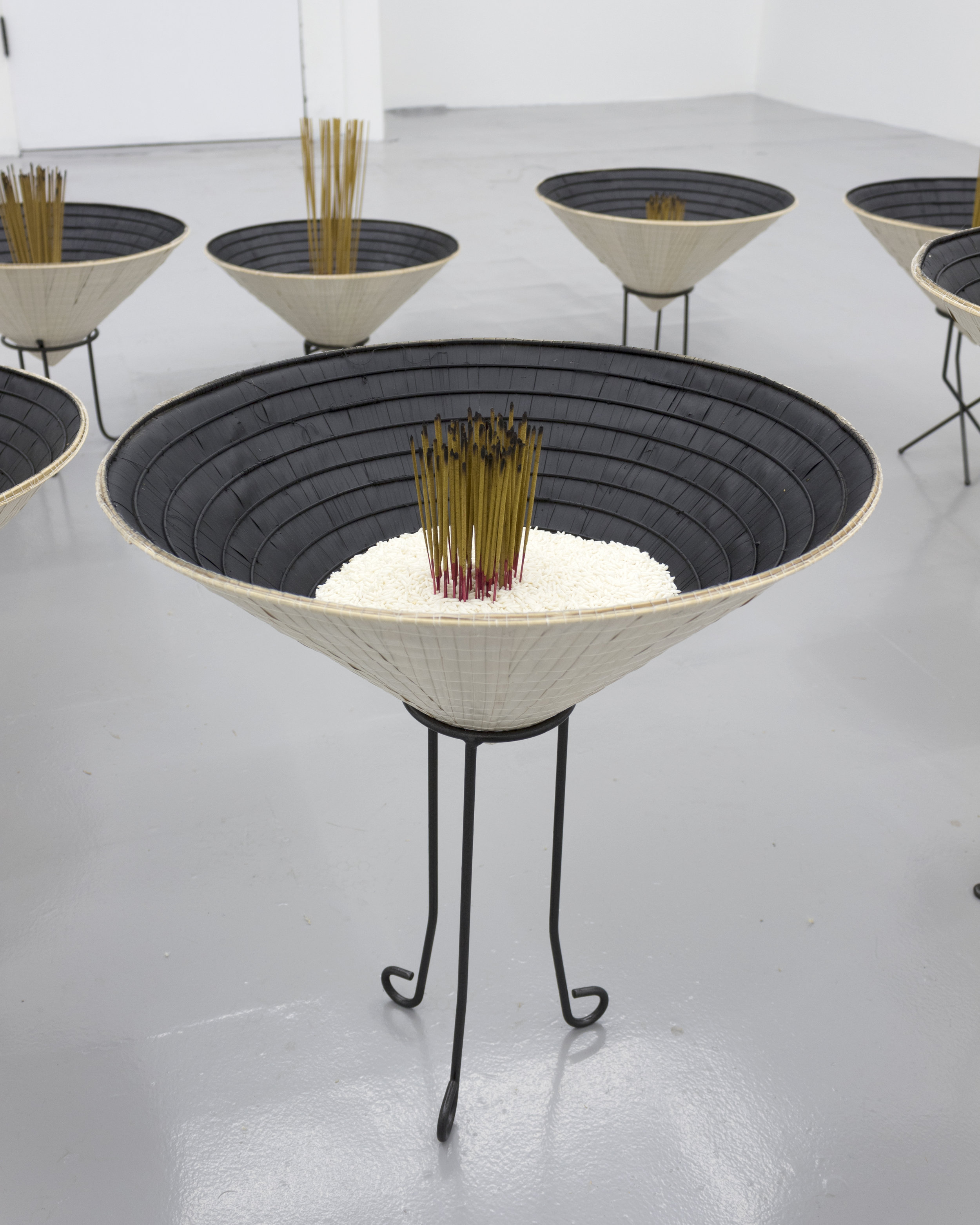  Millian Giang Lien Pham,  Reforge: 9 Phases (Five),  2019. Conical hat, sweet rice, incense, metal stand 