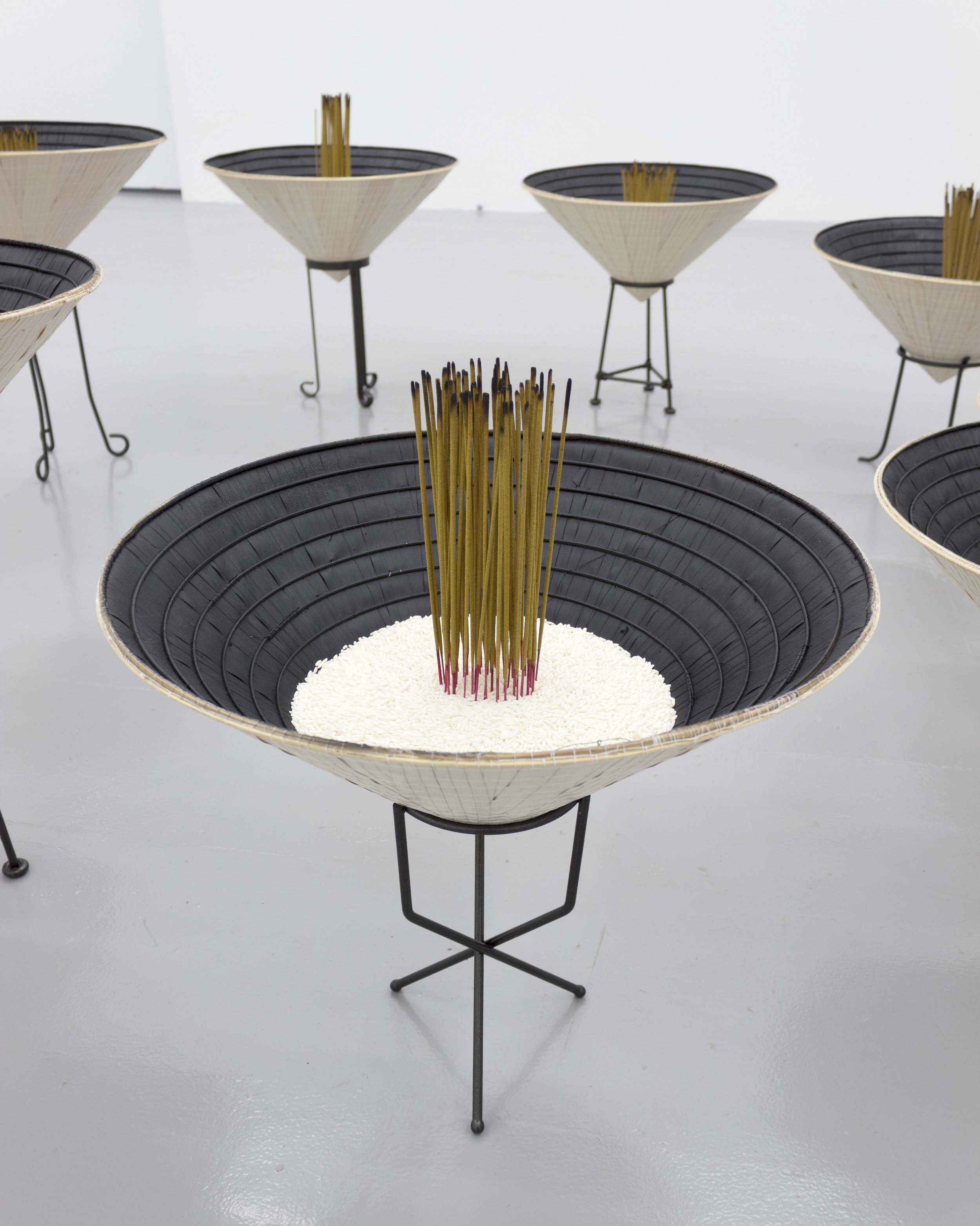  Millian Giang Lien Pham,  Reforge: 9 Phases (Eight),  2019. Conical hat, sweet rice, incense, metal stand 