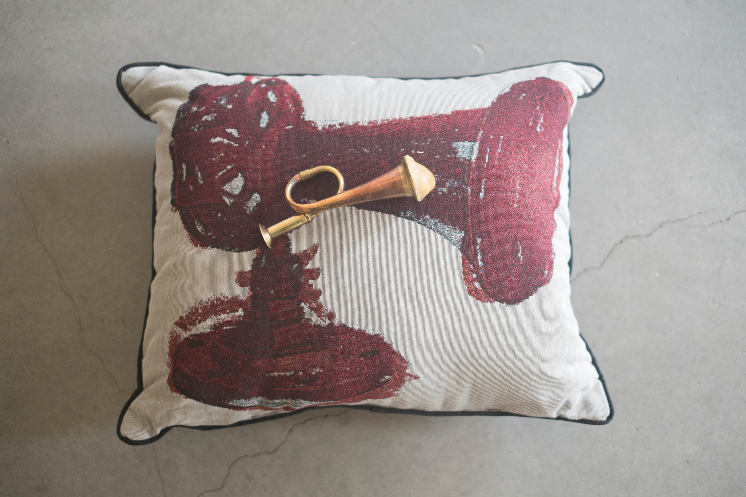   Last Post , 2019, Miniature bugle, cotton Jacquard tapestry pillow, beeswax 