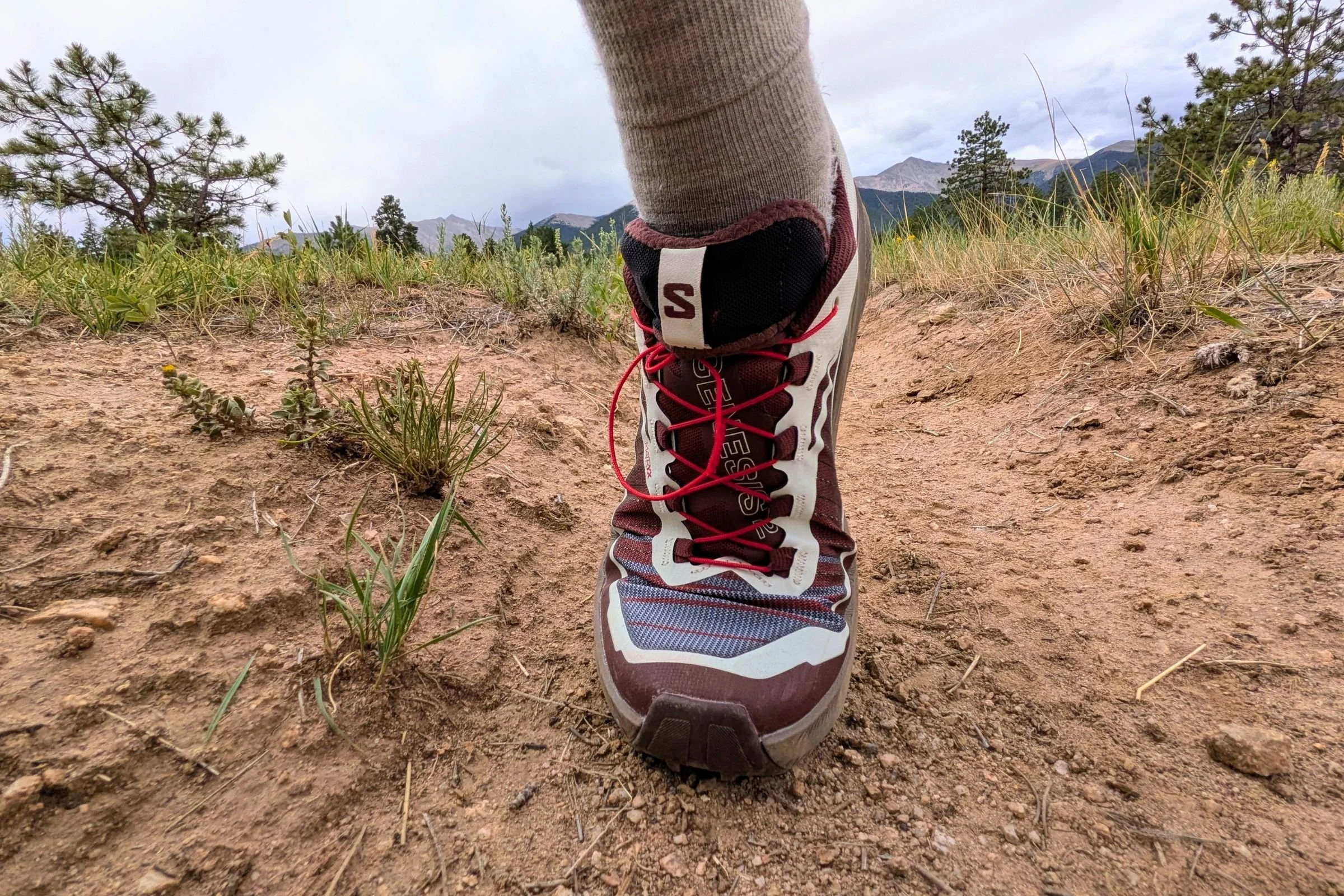 A close view of a person wearing Salomon Genesis 2 Trail Running Shoes on a dirt trail.