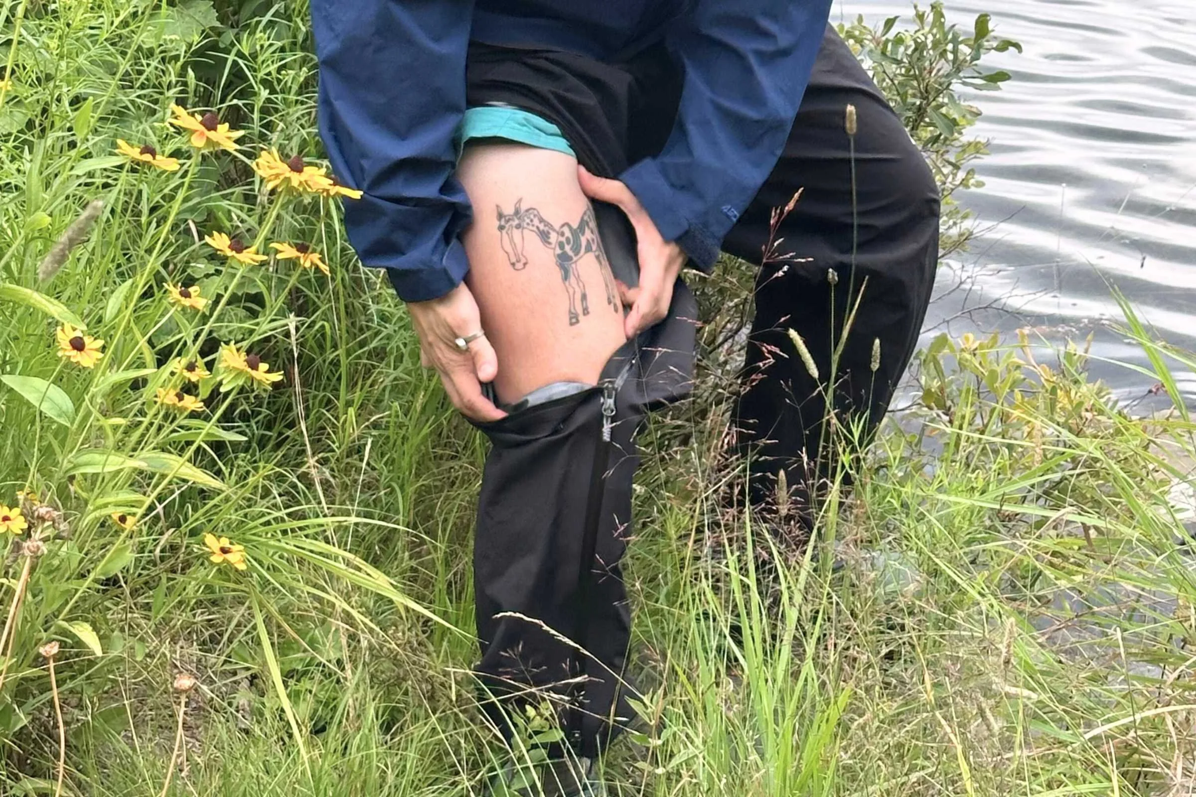Ventilation zipper on the Foray rain pants unzipped to reveal a horse tattoo and hiking shorts.