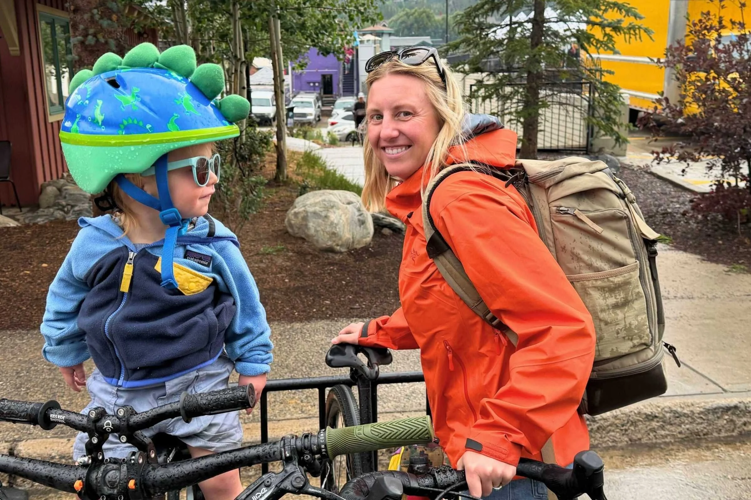 Woman wearing the No Reception Club Travel Backpack while biking with a toddler