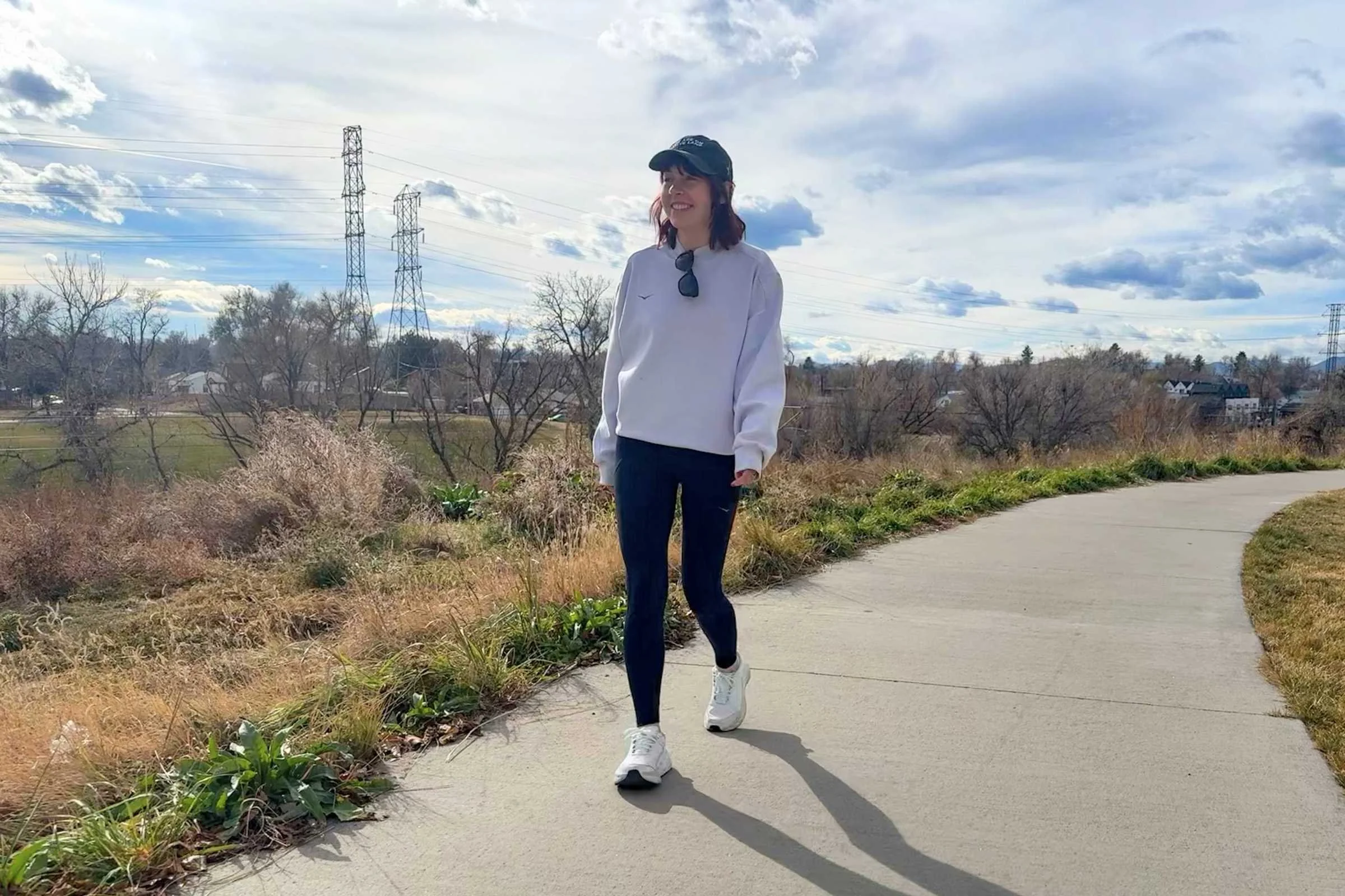 woman walks on bike path in white hoka bondi sr shoes