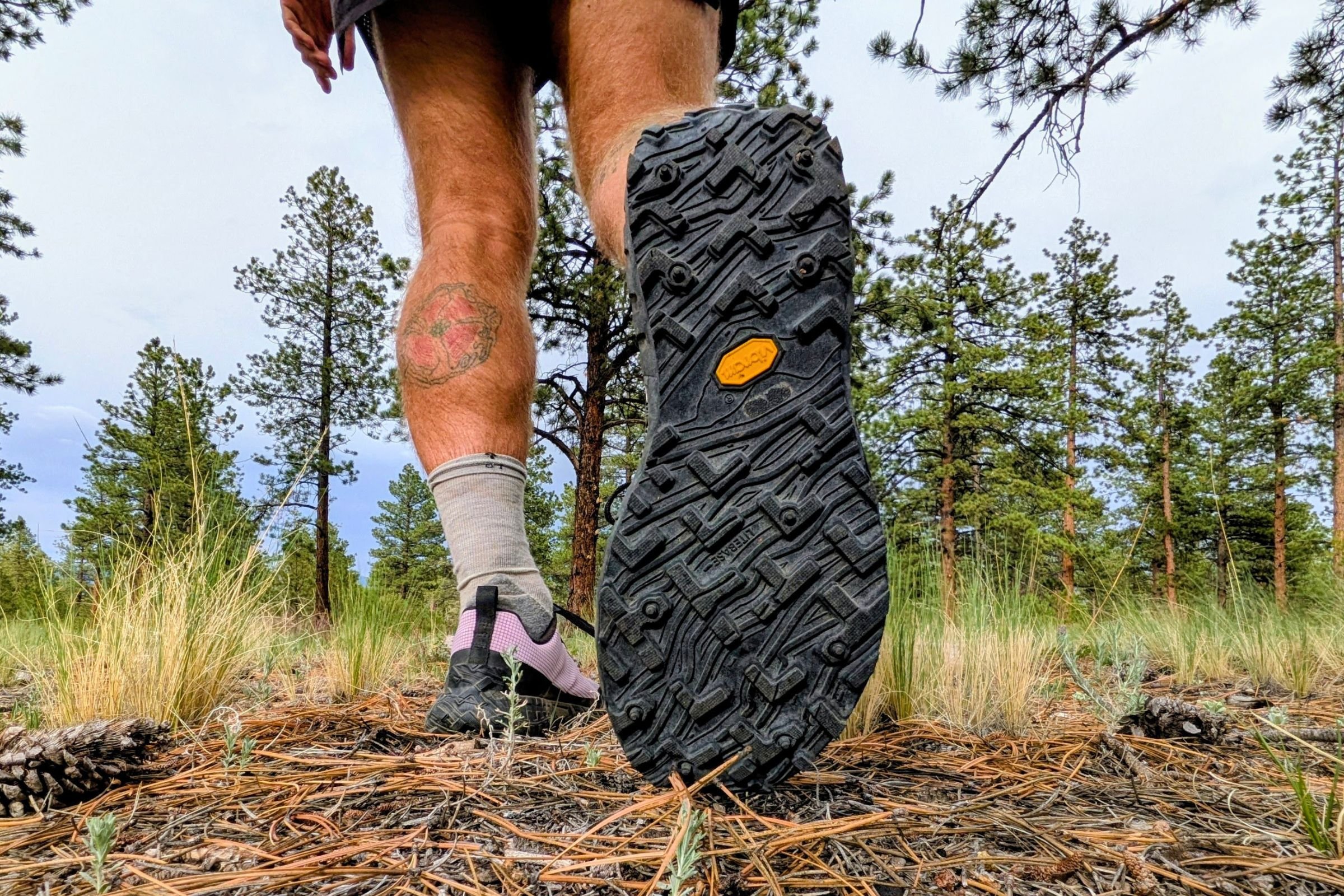 Man wearing Norda 000 Trail Running Shoes showing outsole in a wooded area.