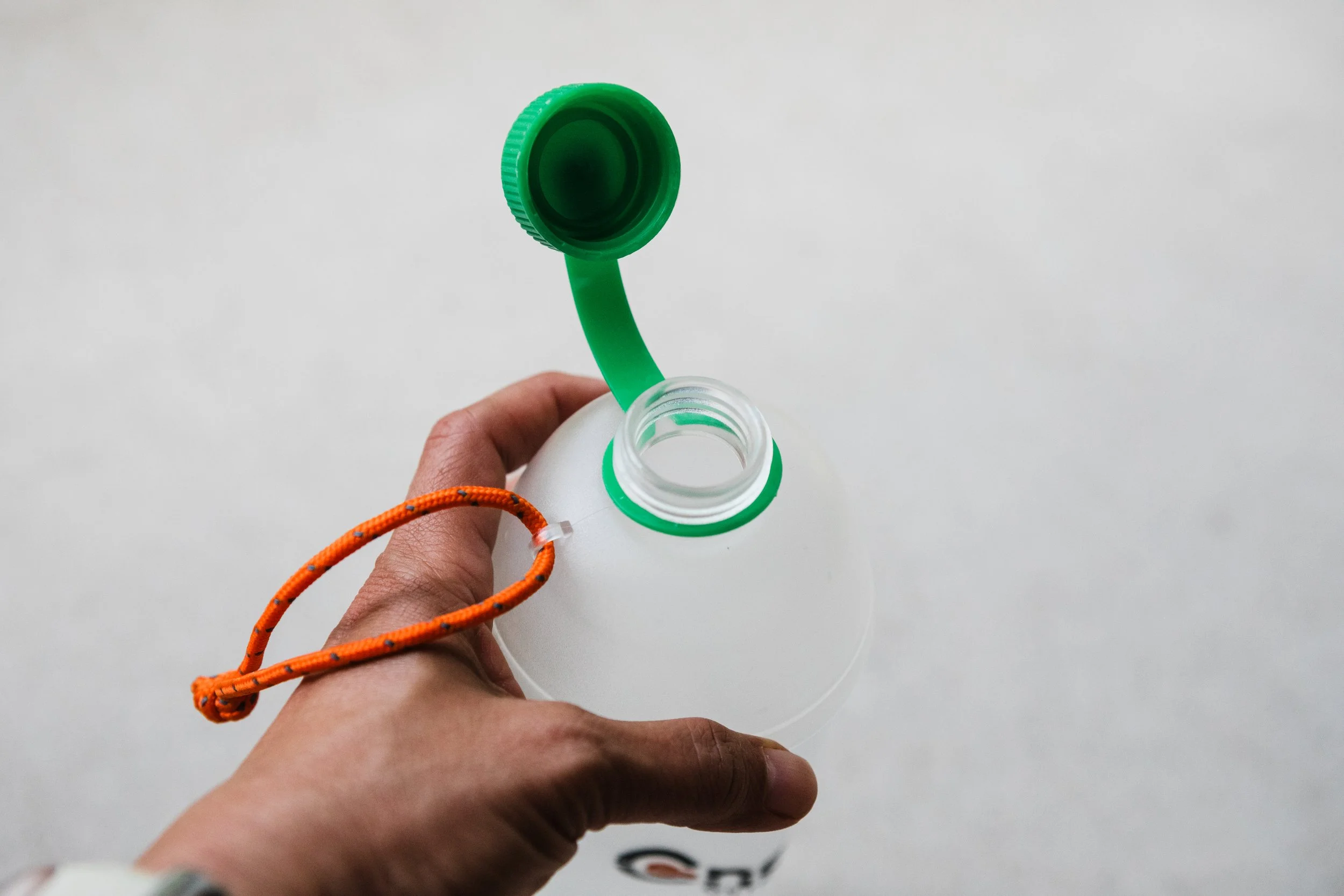 an open cnoc travel water bottle with a green cap and small orange rope loop