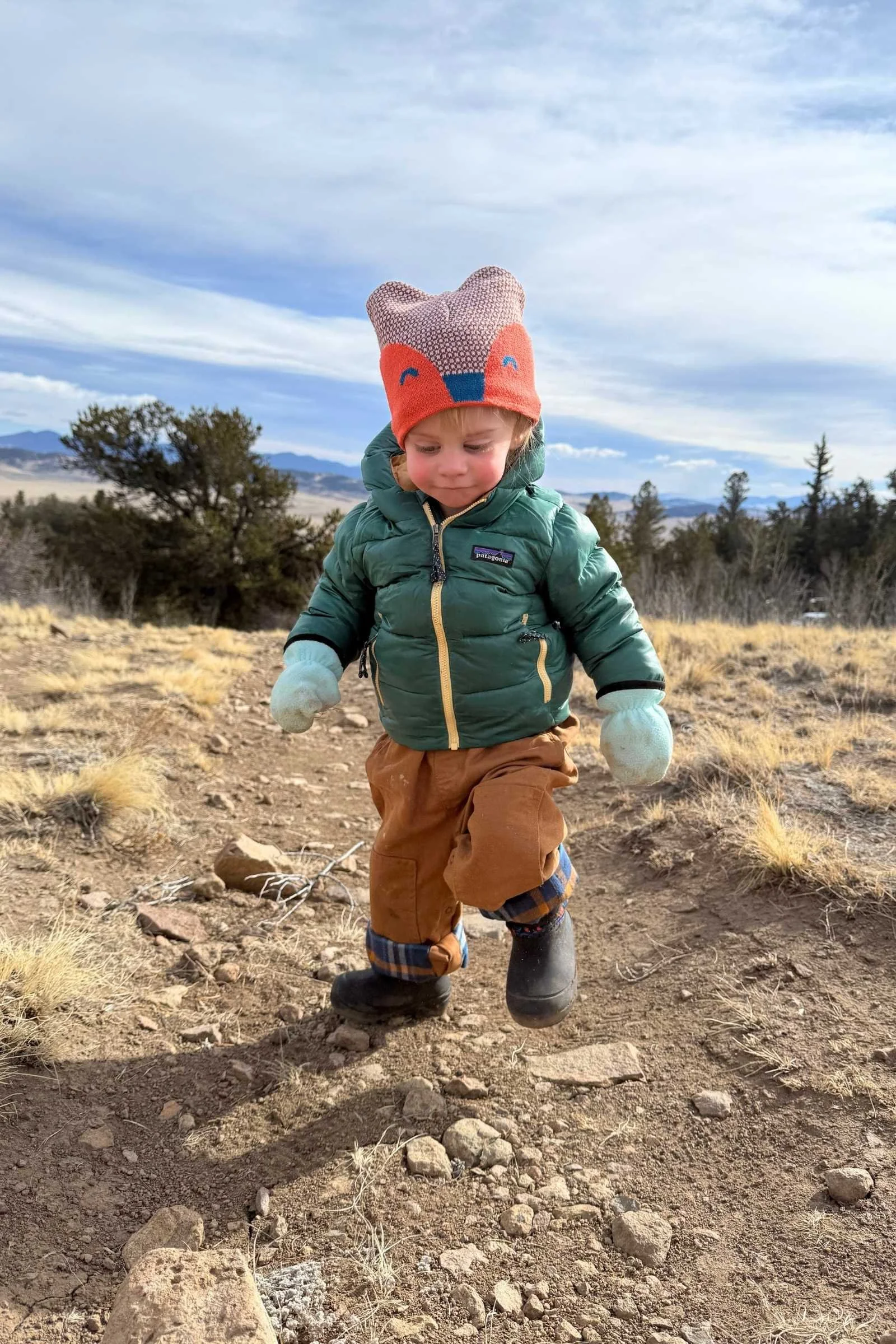 Toddler hiking on rocky trail wearing kids winter snow boots