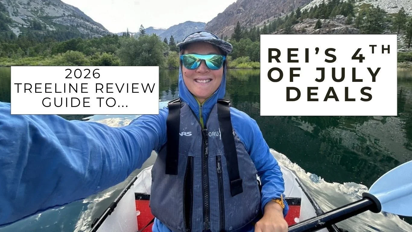 Liz Thomas wearing sunglasses and a sun hoodie in an Oru Kayak on a mountain lake