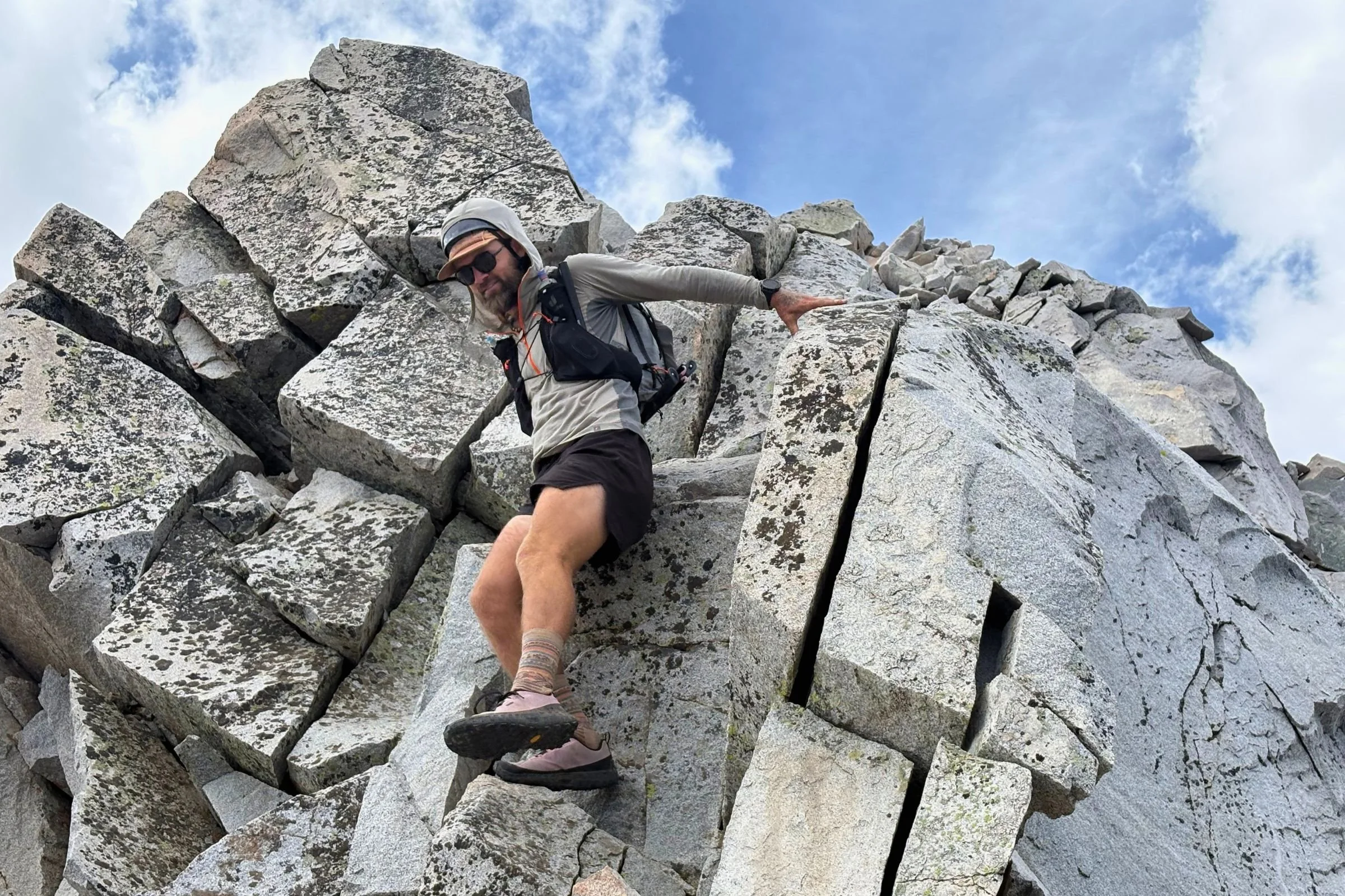 Man climbing a rocky mountain in Norda 000 Trail Running Shoes.