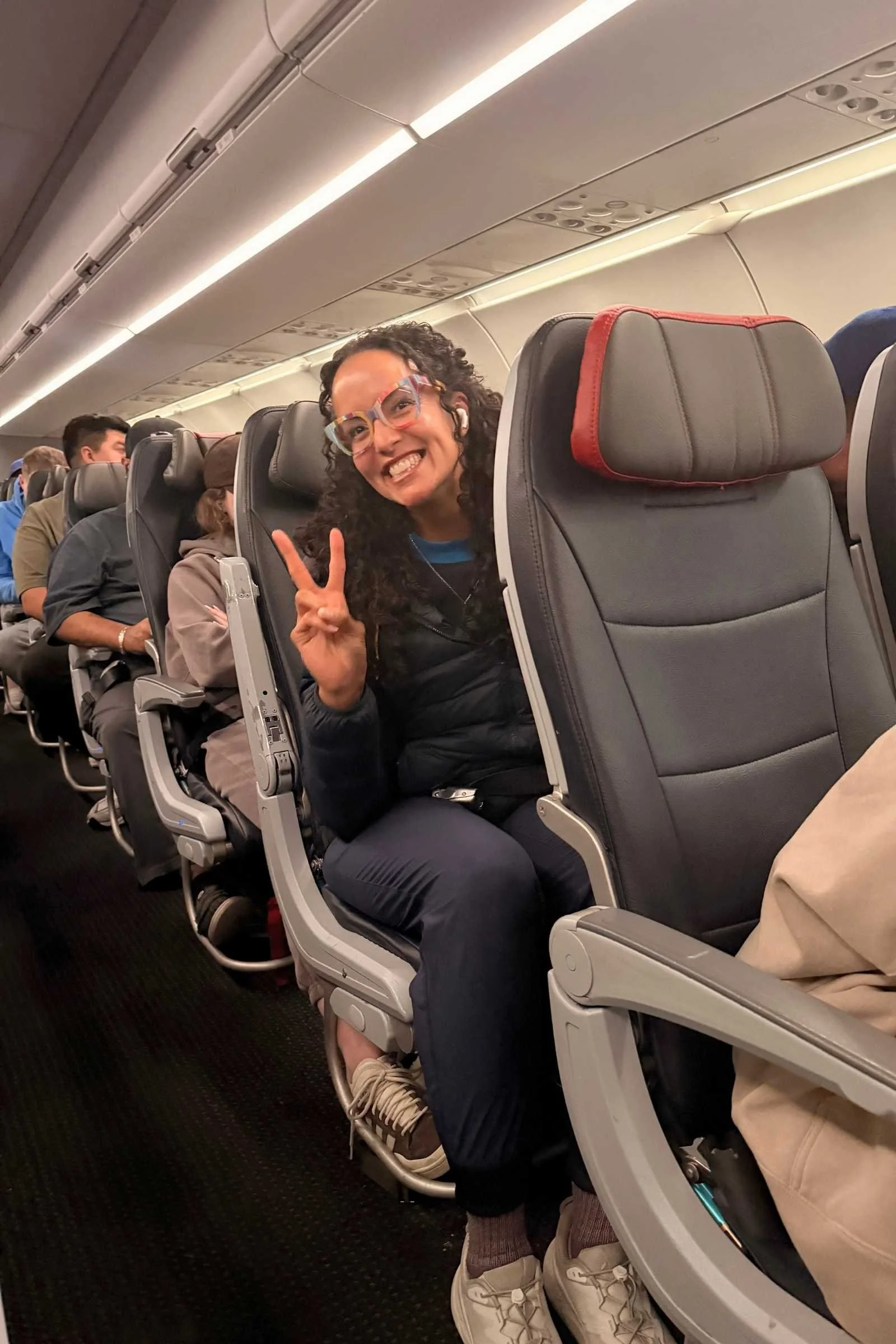 Person seated in an airplane seat wearing travel pants, legs visible and relaxed