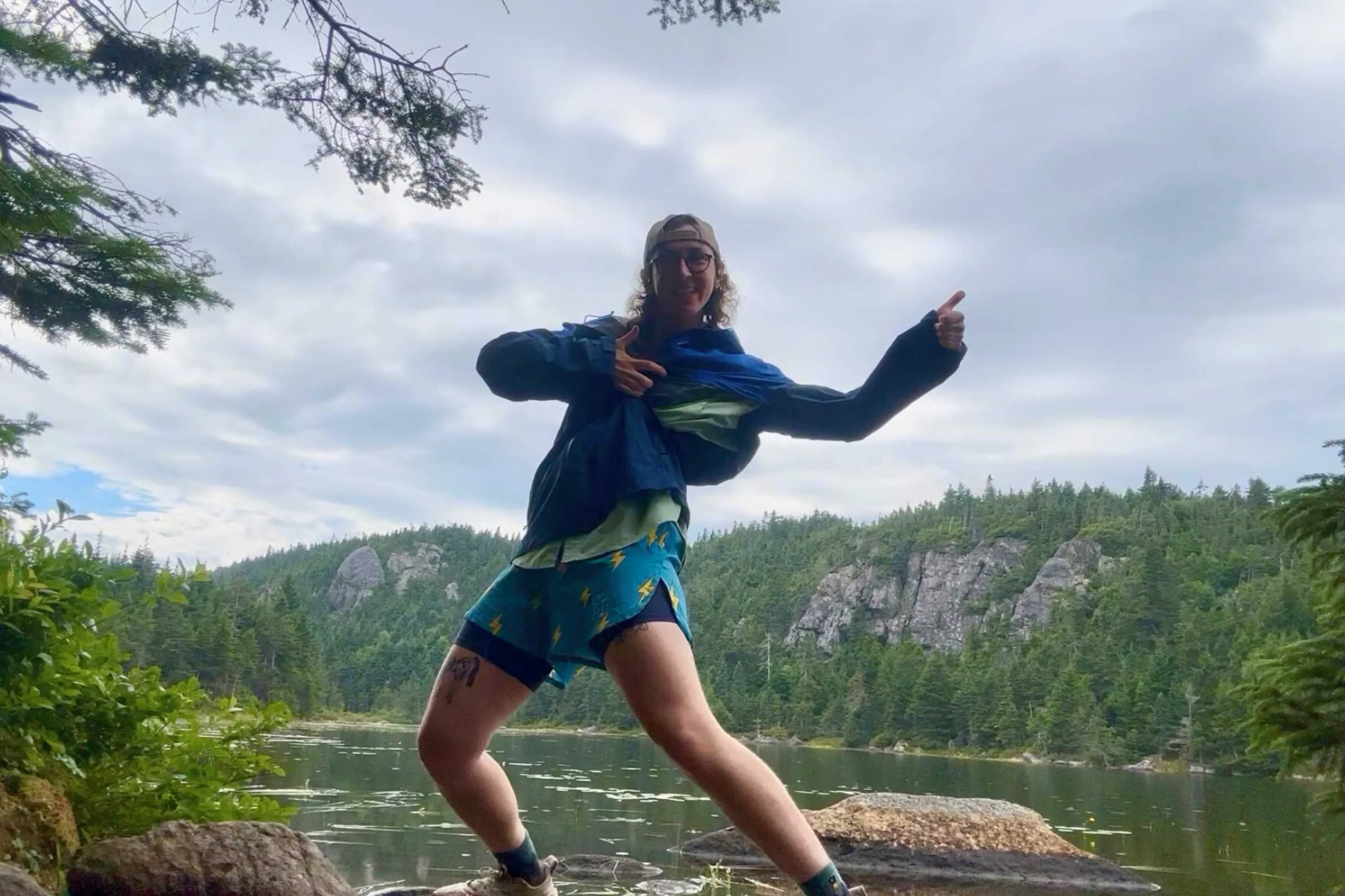 Elliot in shorts and Foray rain jacket with the pit zips undone in front of Horns Pond
