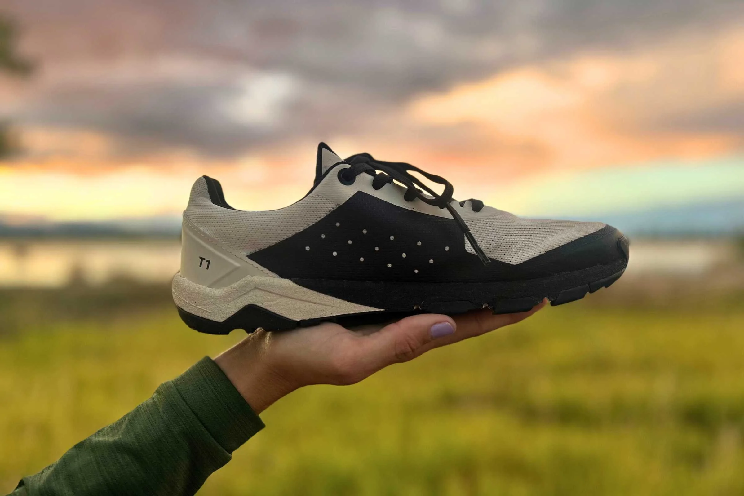Notace Yama T1 trail running shoe being held up in profile at sunset