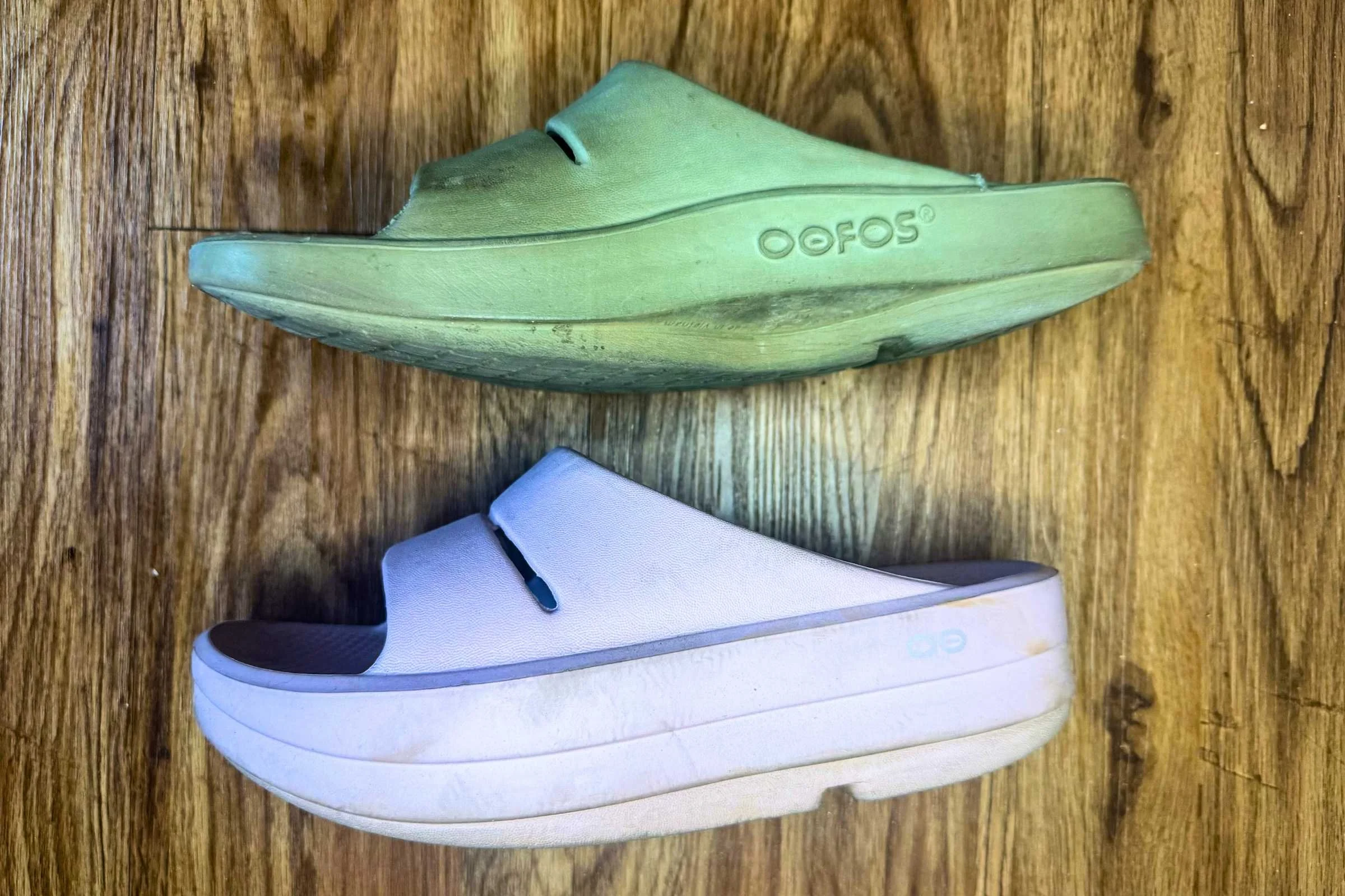 The OOFOS OOmega slides (bottom) offer 15 mm more cushion than the OOahhs (top).