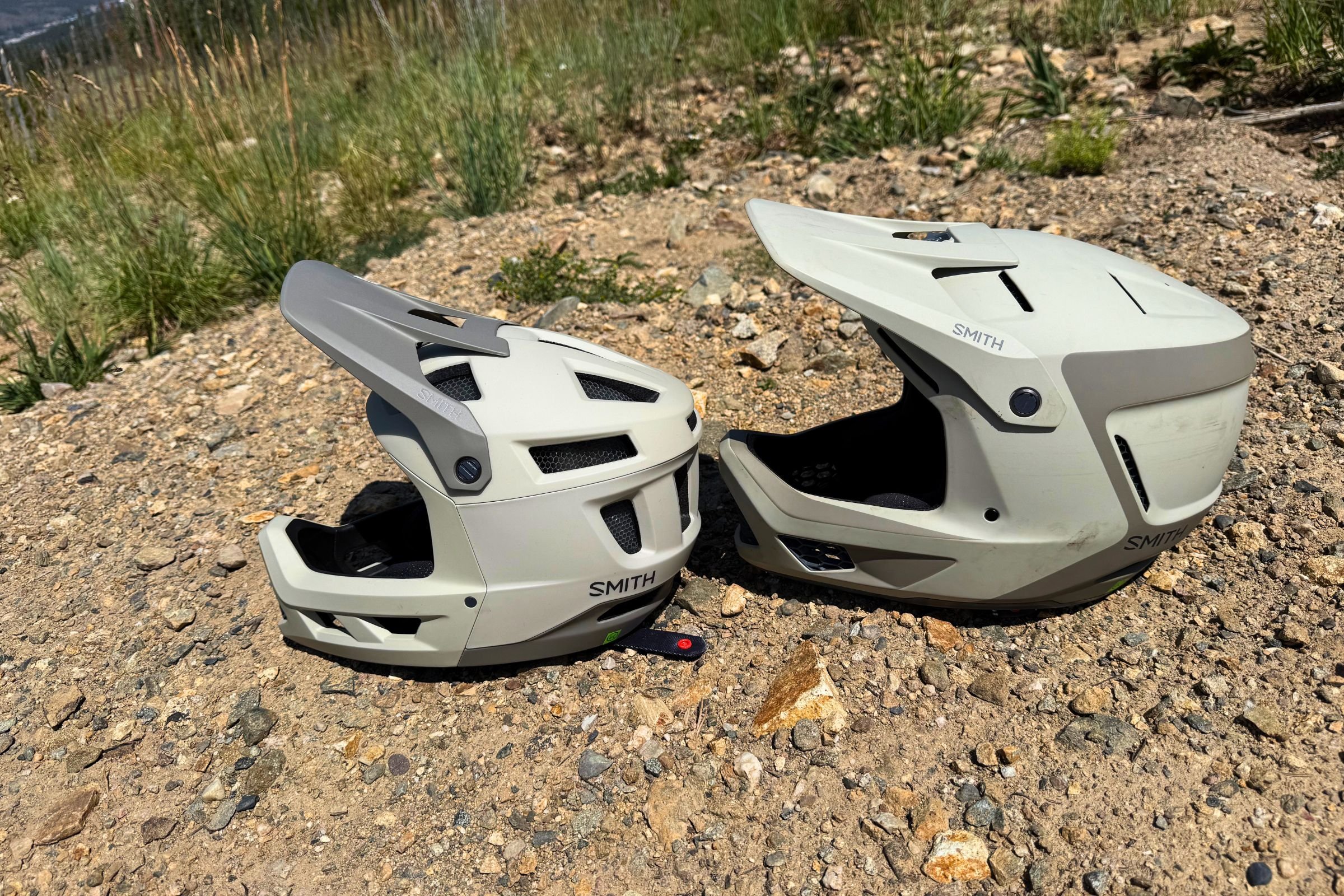 The Smith Hardline (left) and Smith Mainline Mips (right) helmets with rocks and grass in the background.