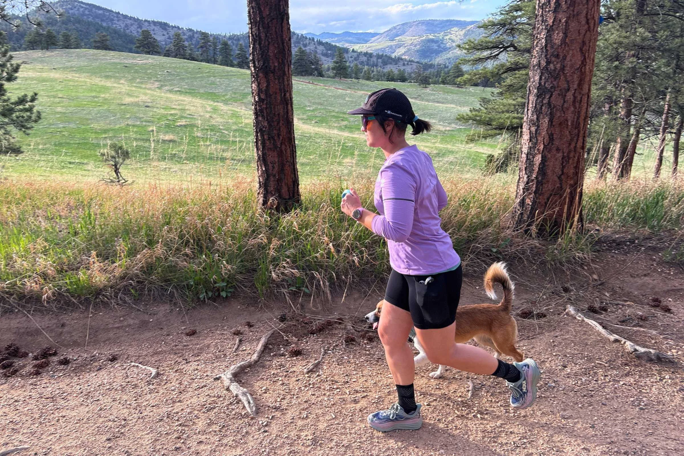 A person running on a dirt path with a dog