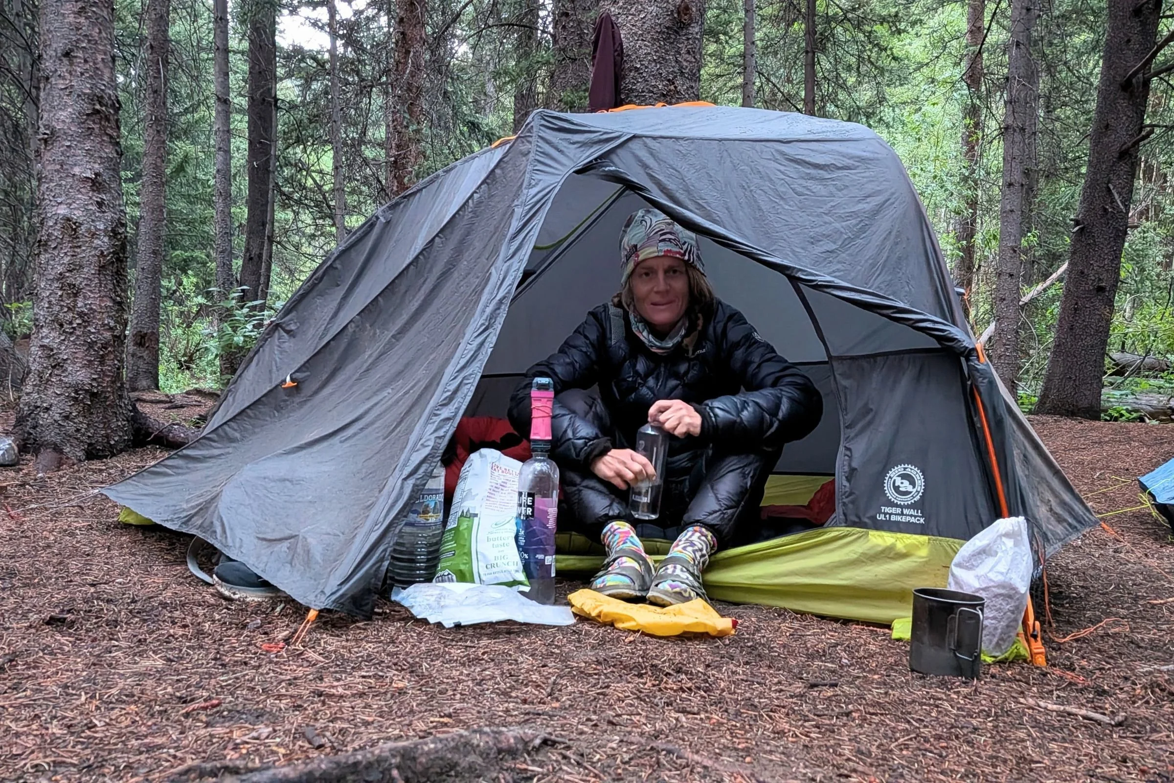 The Big Agnes Tiger Wall UL1 Bikepack Tent with a person sitting inside and trees in the background.