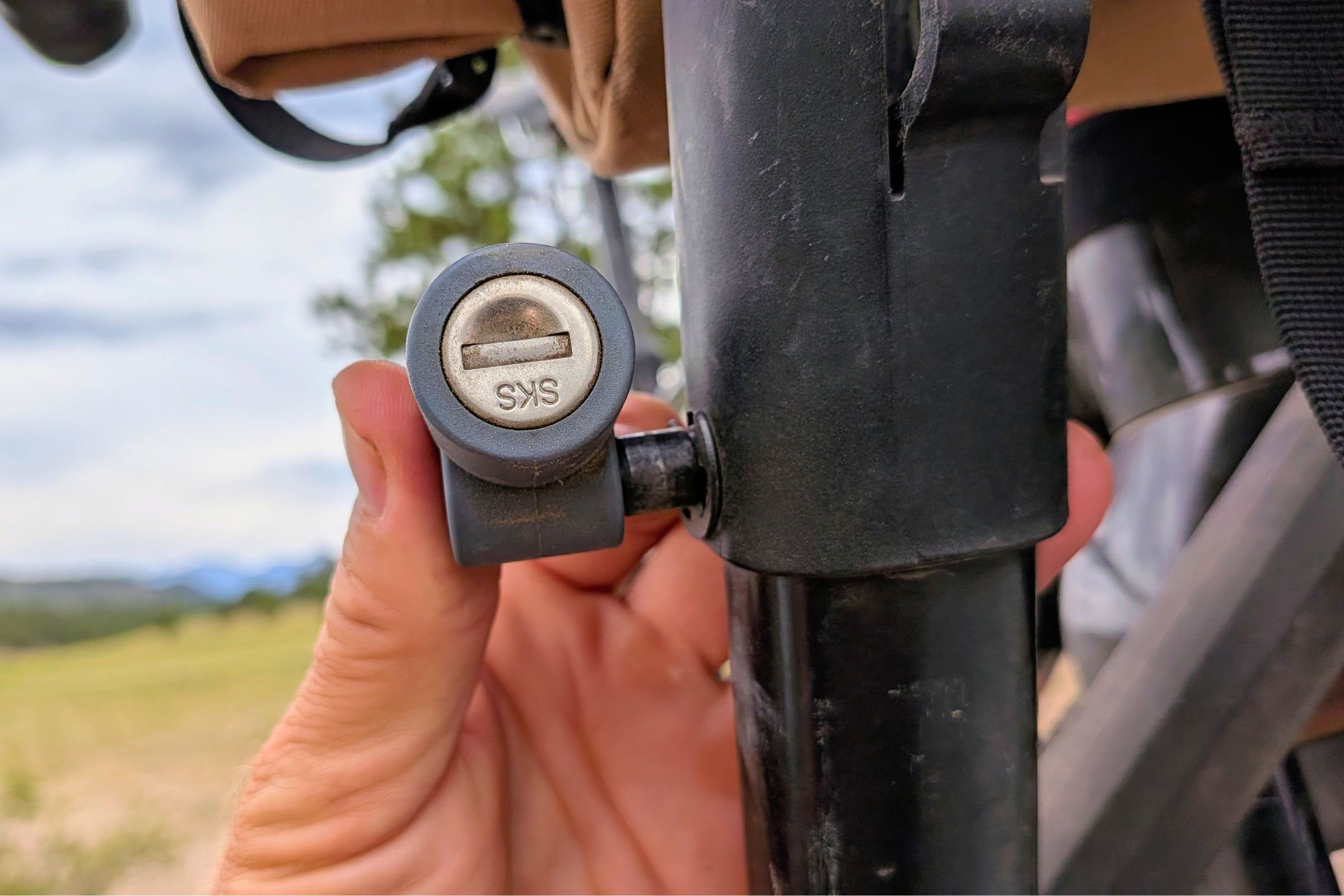A person holds a bicycle lock secured to a bike mounted on a Yakima EXO DoubleUp 2-Bike Hitch Rack.