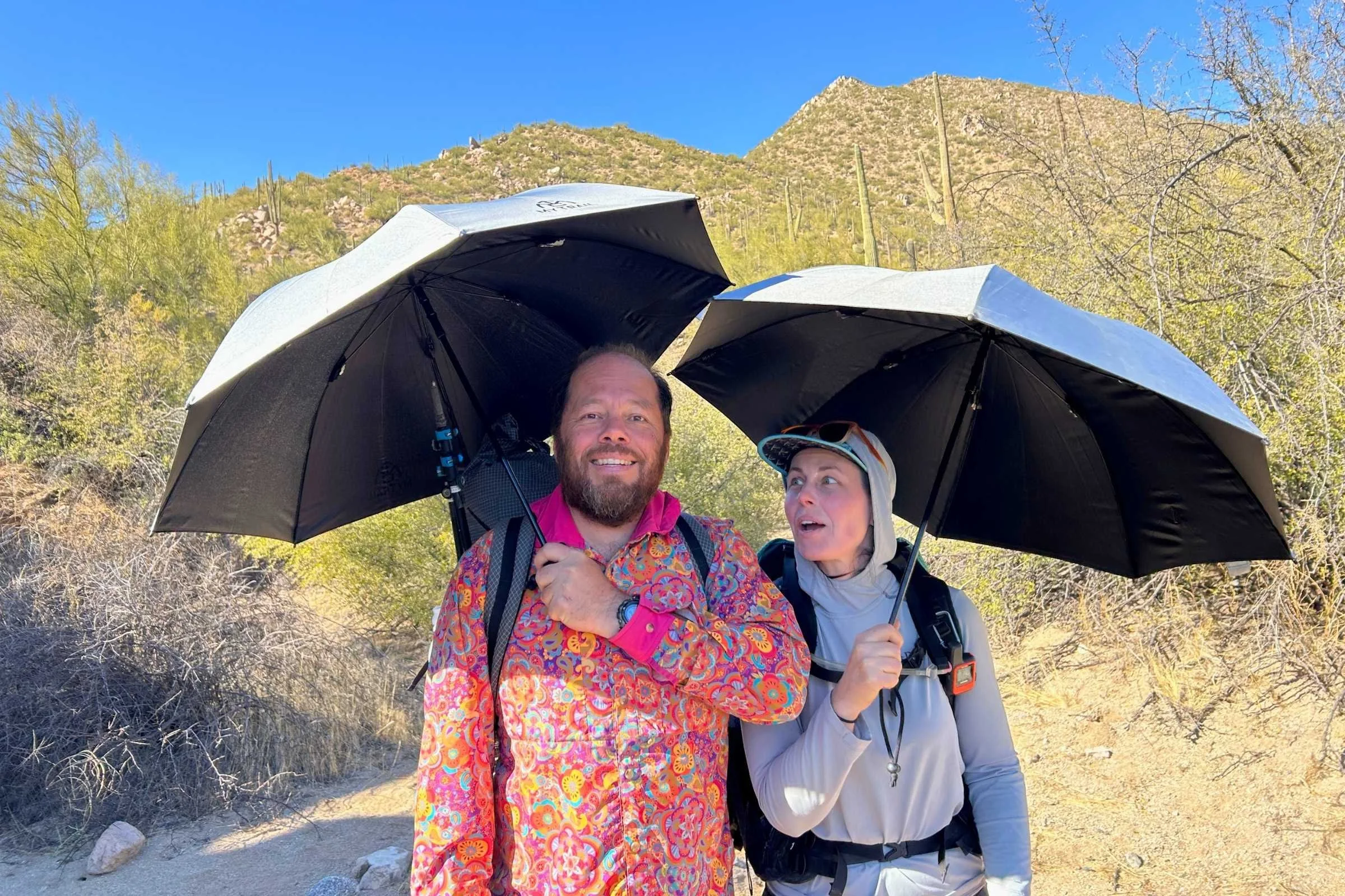 Two hikers under hiking umbrellas