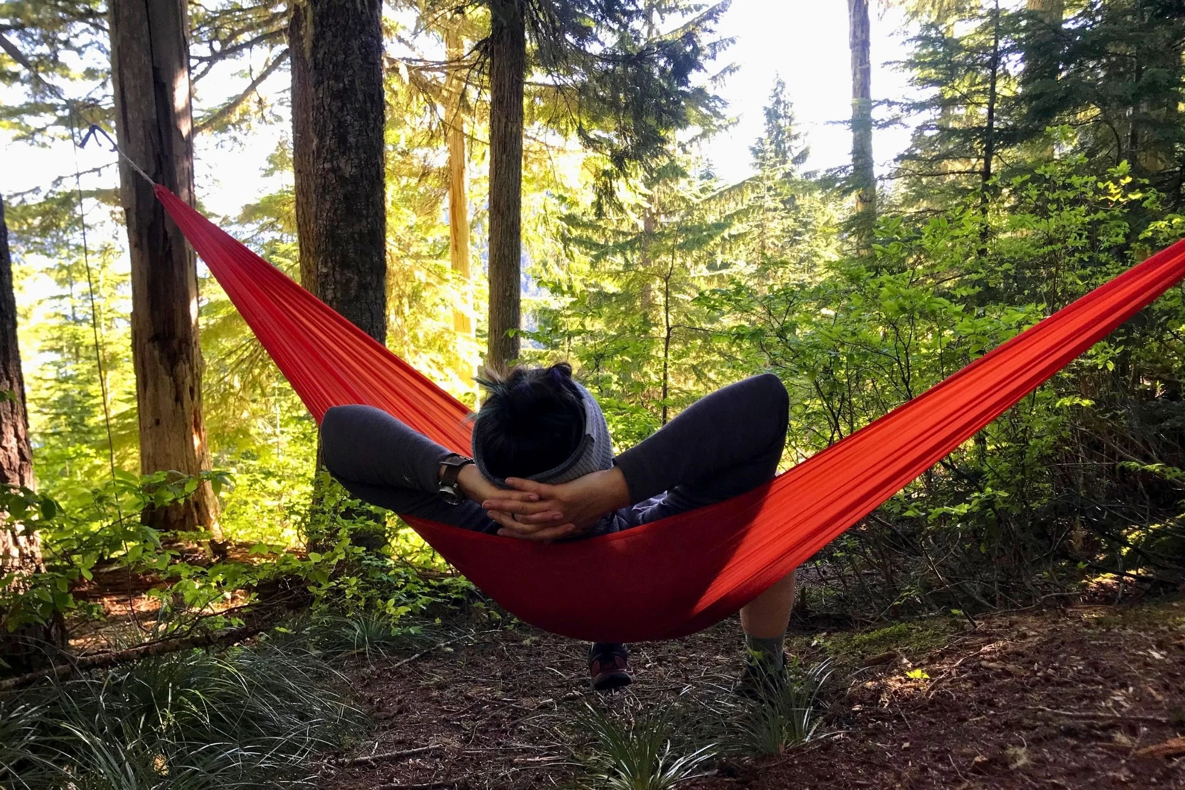 A tester relaxes in the ENO Sub6 Ultralight Hammock in a forest.