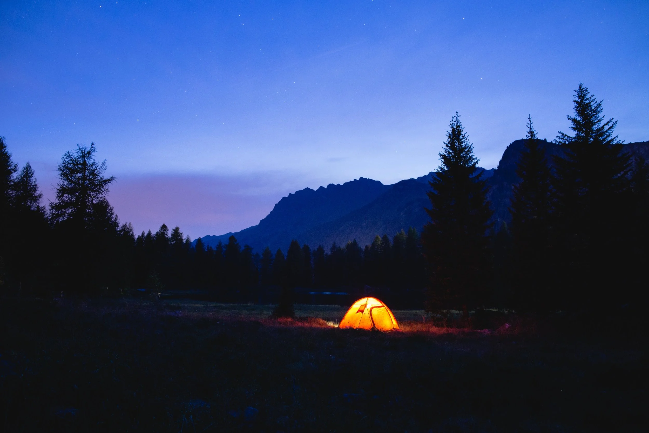 An illuminated tent under a darkening sky.