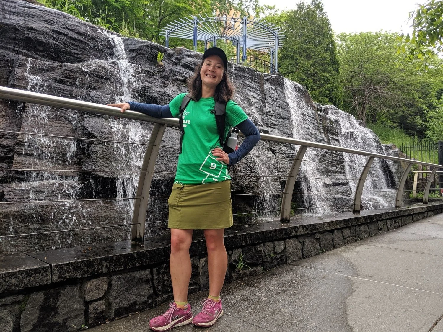 Liz Thomas wearing the Lululemon Swiftly Tech long sleeve shirt standing next to a waterfall in New York City.