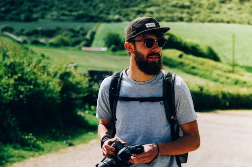 A man wearing a travel backpack with a camera.