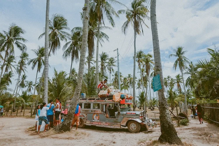 Travel bus loaded with travel backpacks in a tropical scene.
