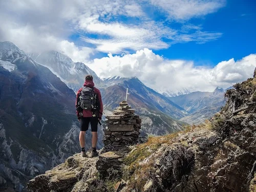 Person standing in an alpine mountain scene wearing a backpack.