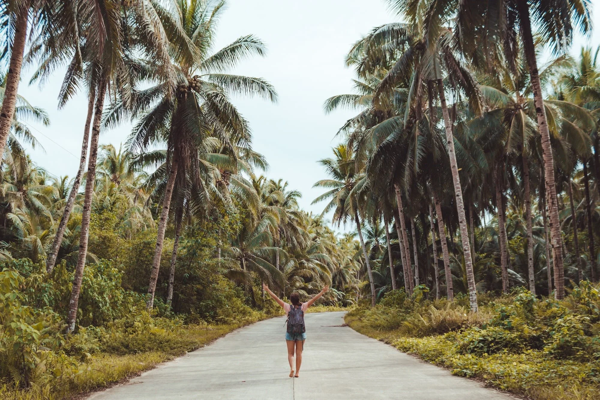 Woman wearing a travel backpack in a tropical scene.