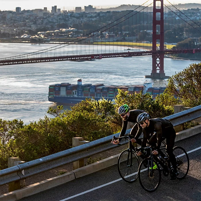Two bicyclists wearing the Bell Stratus MIPS with the Golden Gate Bridge in the background.