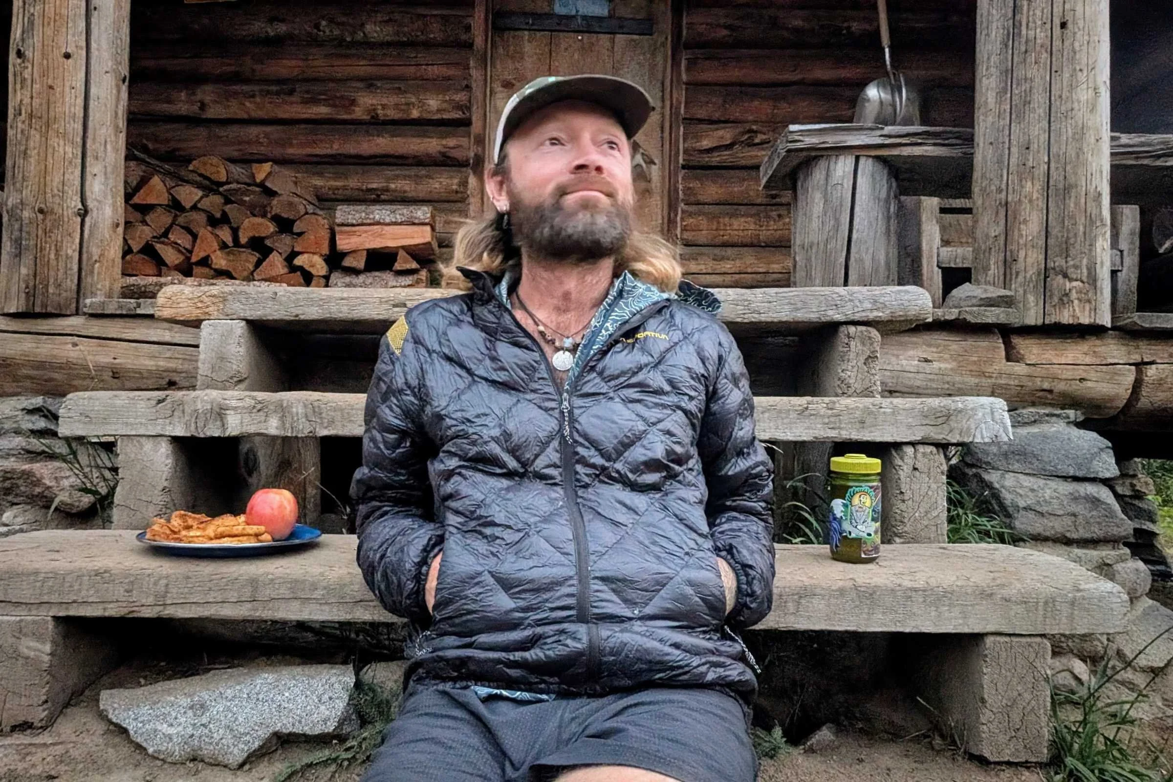 Man resting at rustic cabin wearing La Sportiva Lumina down jacket