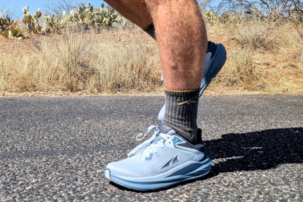 Man wearing the Altra Torin 2 running shoes in grey while running on a paved pathway.