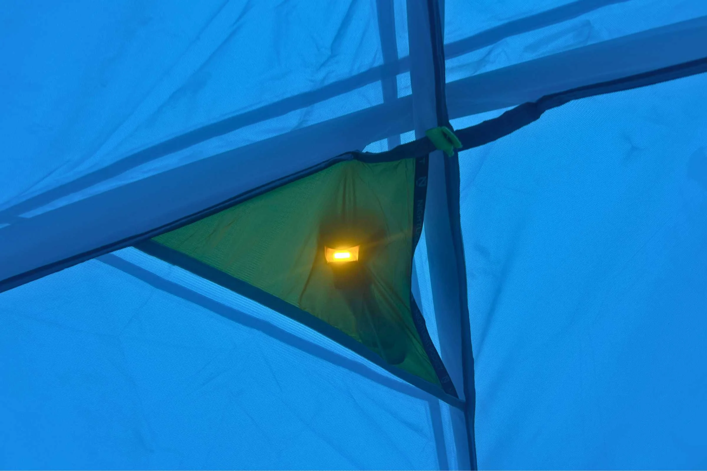 Headlamp shining down from the ceiling of the NEMO Aurora Highrise camping tent