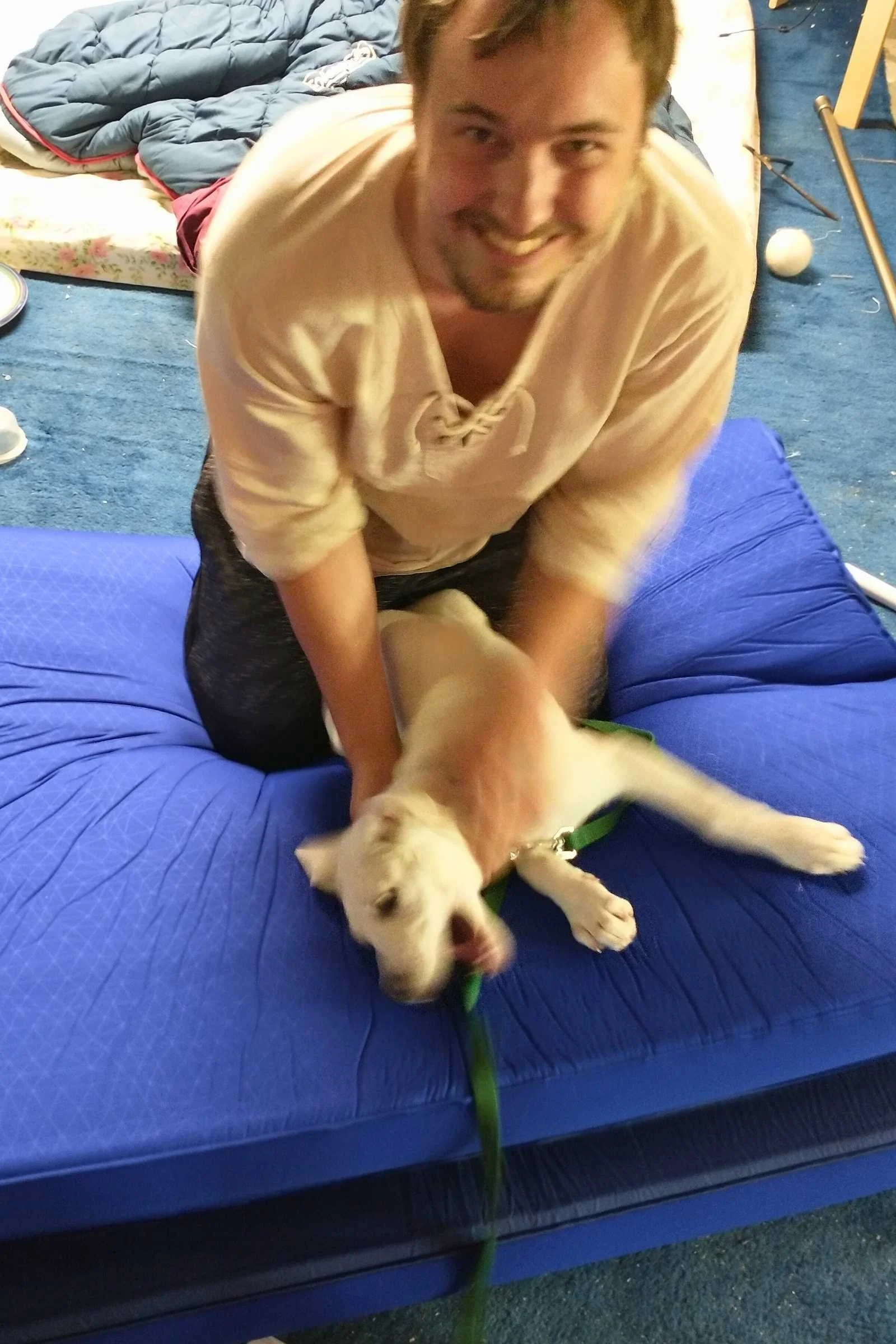 Man wrangling a puppy playing on the Sea to Summit Comfort Deluxe sleeping pad