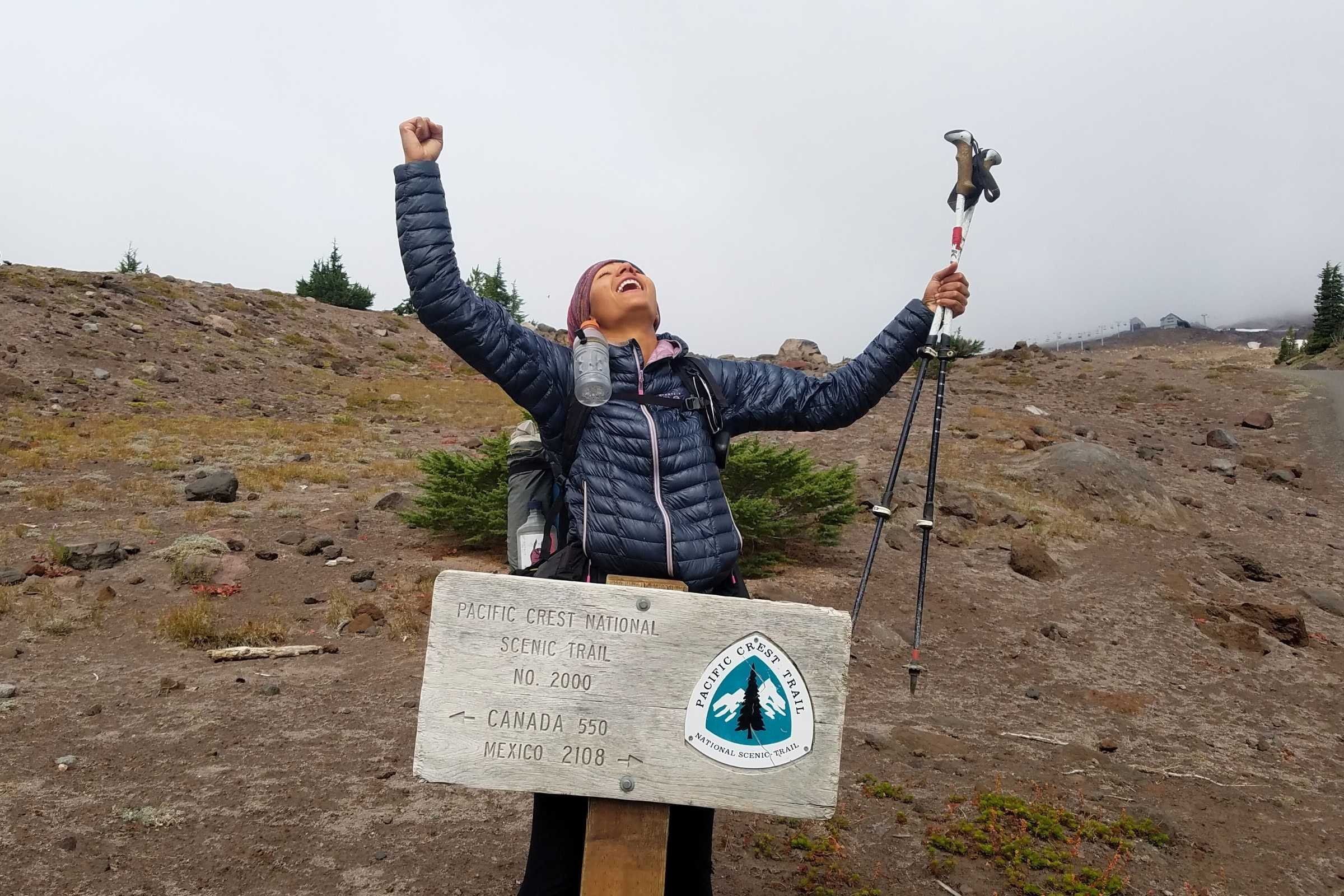   Amanda “Zuul” Jameson celebrating a PCT milestone in the Ghost Whisperer. The Mountain Hardwear ultralight jacket is a favorite among thru-hikers.   Photo courtesy Amanda Jameson  