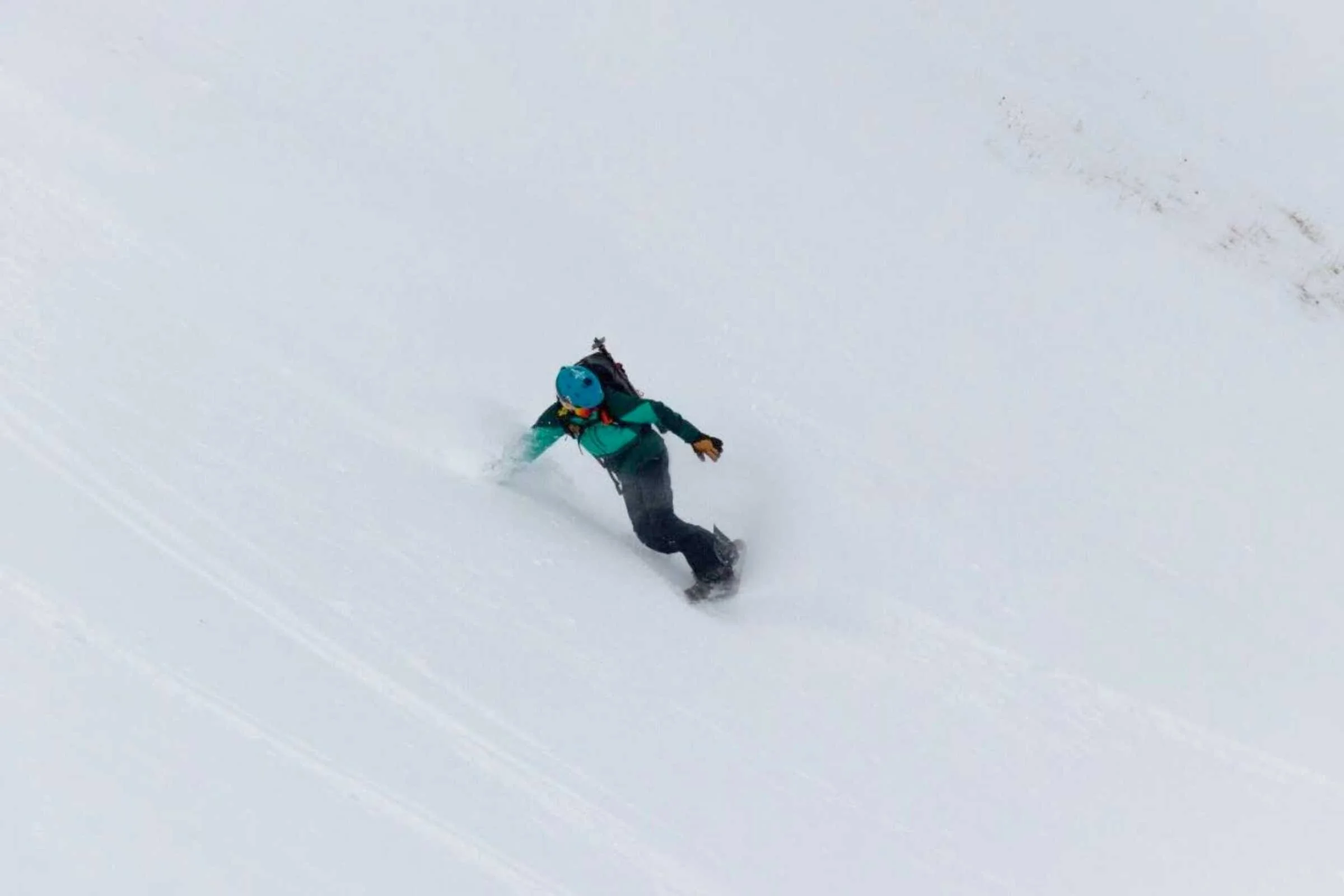   Author Dani Reyes-Acosta snowboards on a beautiful descent wearing Osprey Sopris Pro avalanche ski pack.   Photo by Nate-DeCremier  