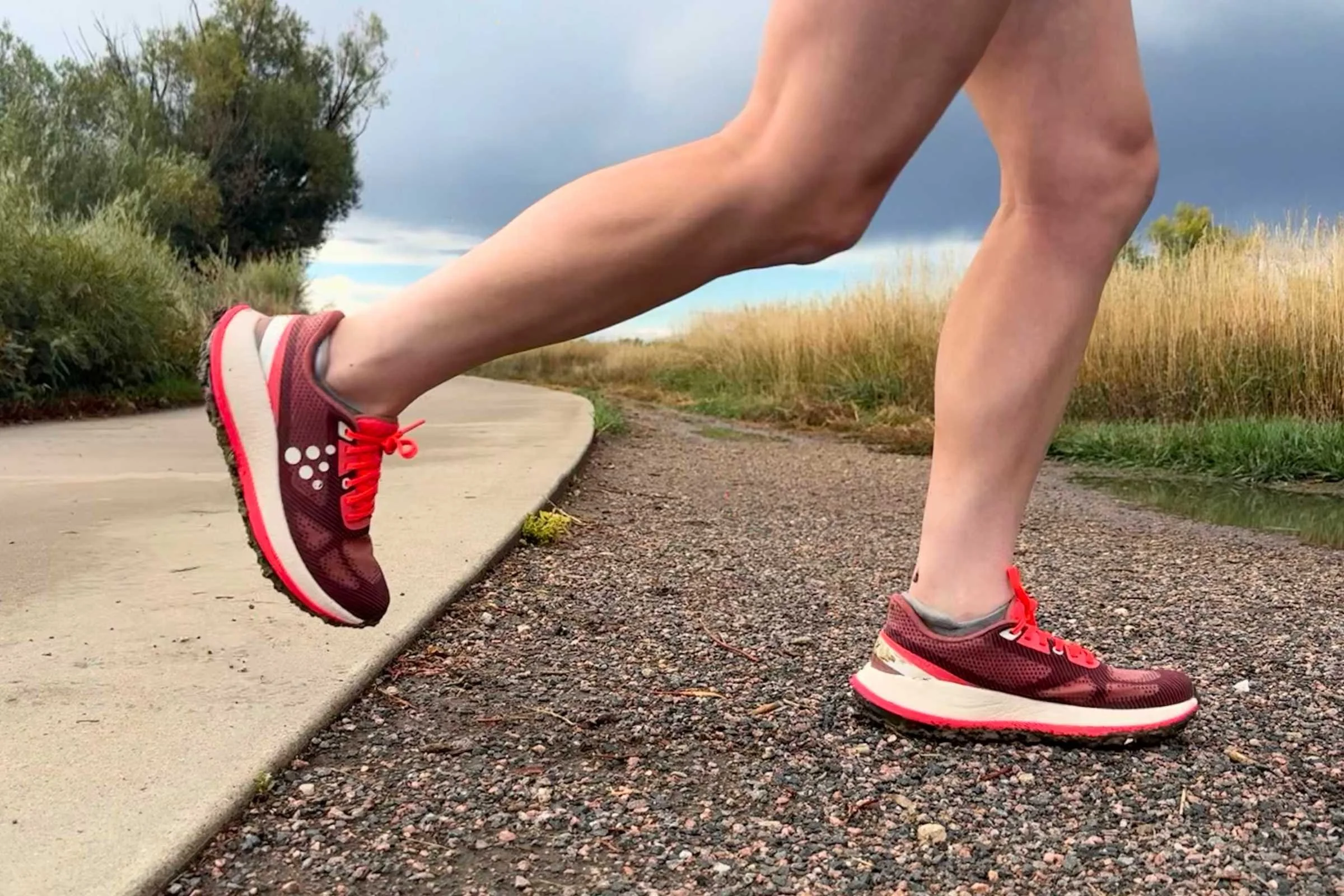  red pair of Craft Xplor 2 running shoes transitioning from sidewalk to gravel 