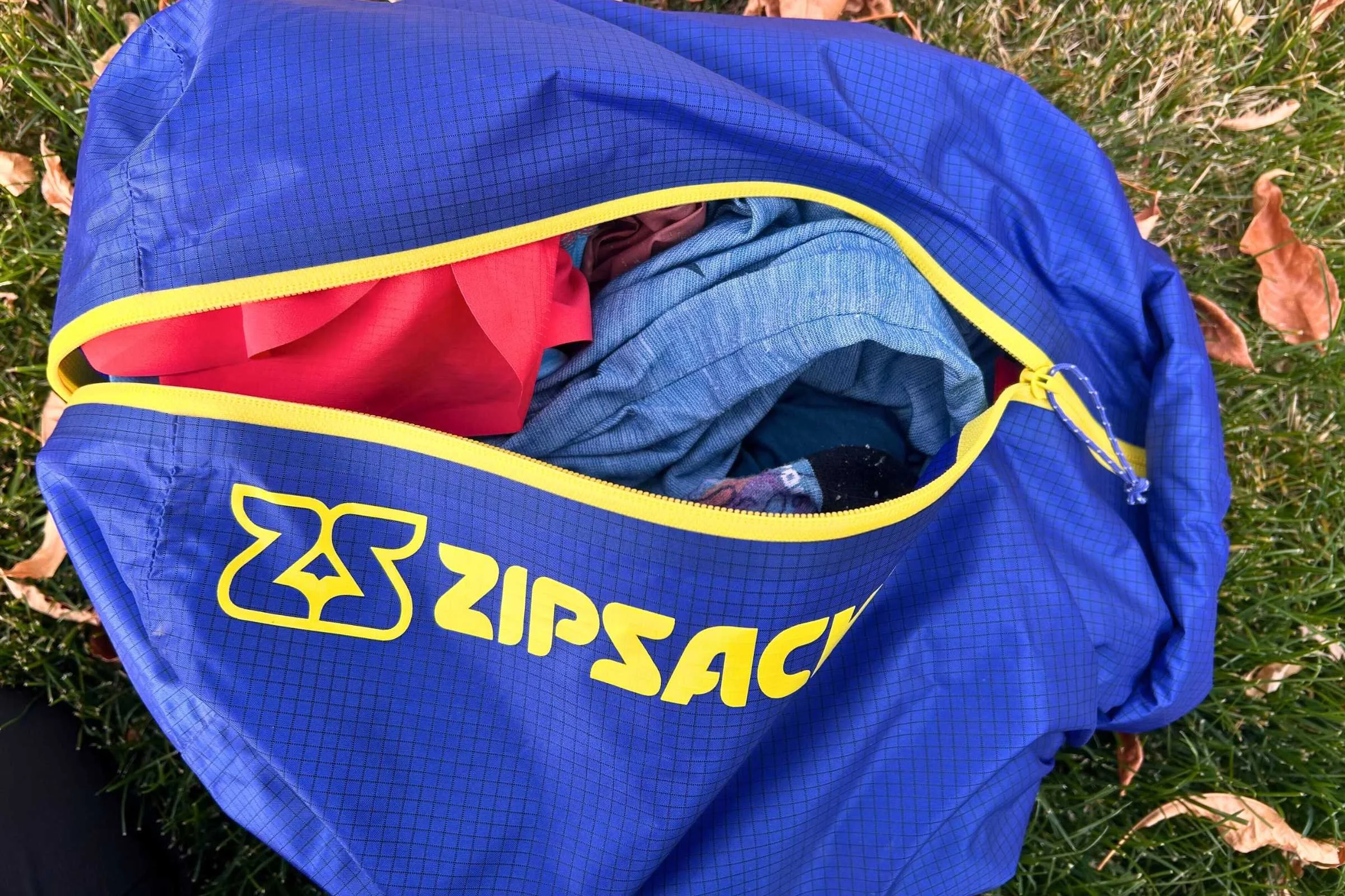  close up of a blue Zipsacks 20L Stuff Sack with a yellow logo and zipper    