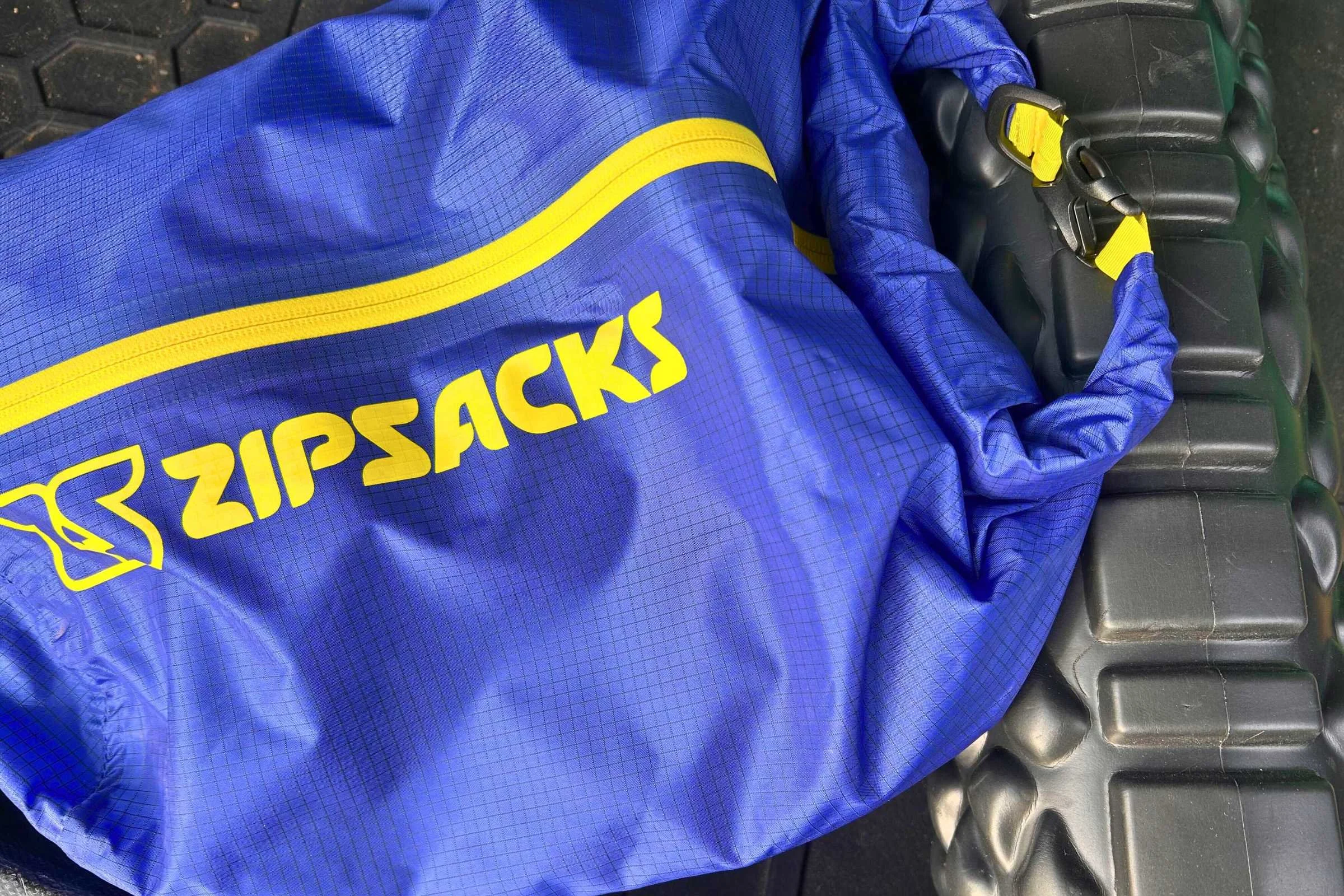  close up of a blue Zipsacks 20L Stuff Sack with a yellow logo and zipper    