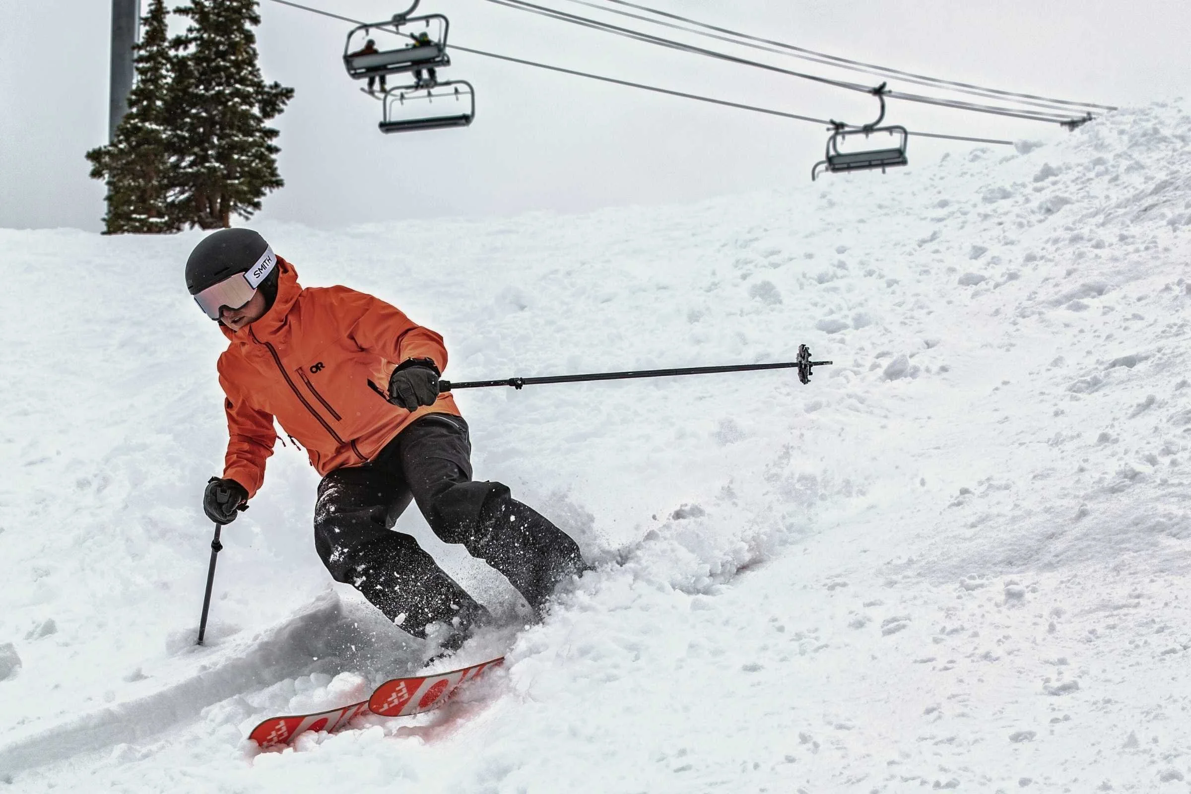   Skier carving through powder in Outdoor Research Hemispheres Team 3L jacket  
