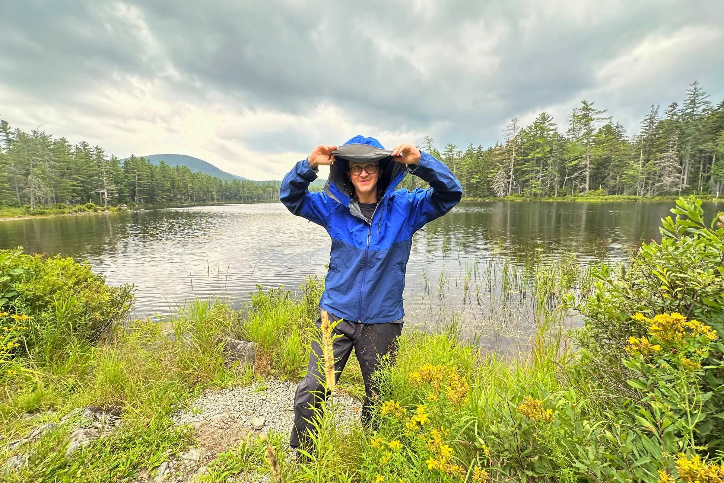  person testing the waterproofness of the outdoor research foray 3l rain jacket on a rainy day in the woods 