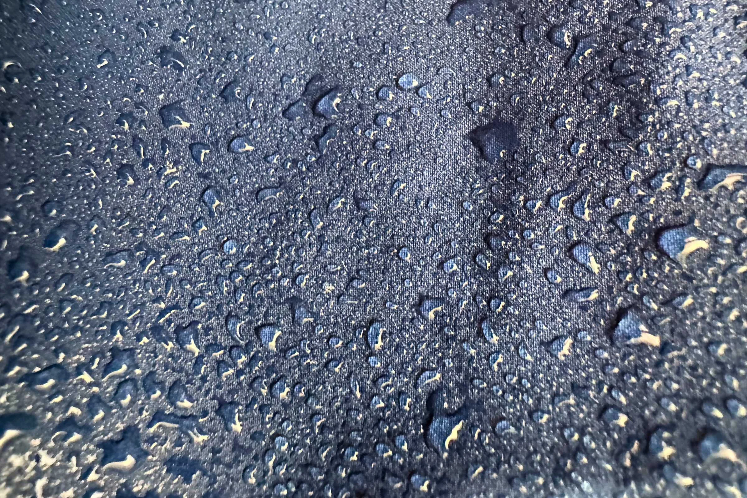  person testing the waterproofness of the outdoor research foray 3l rain jacket on a rainy day in the woods 