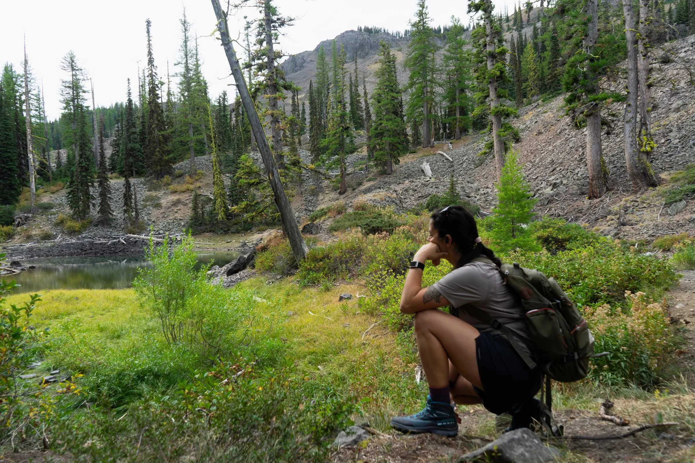   Hiker squatting and enjoying the scenery while hiking in the La Sportiva TX Hike Mid boots  